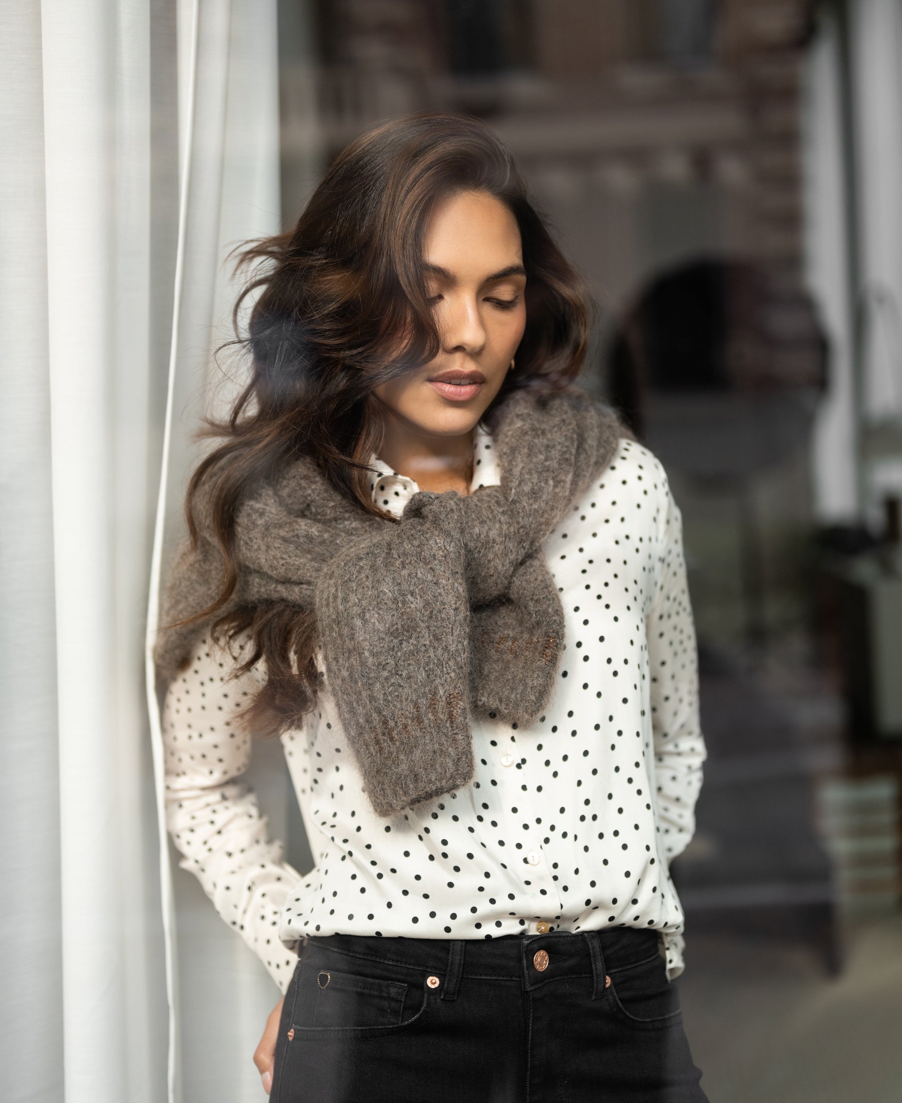 Ivory-black polka dot blouse with relaxed fit, shown in a side view by a window.