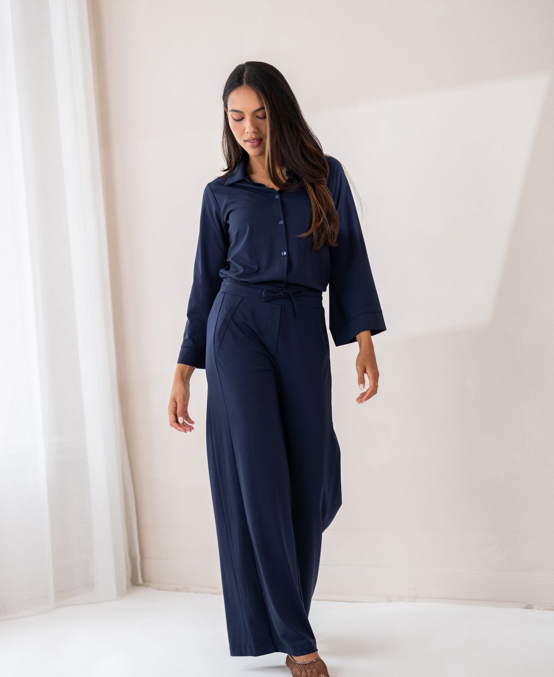Navy blue PLEIN PUBLIQUE LA SILVESE travel blouse shown indoors. Model looks down in a relaxed pose.
