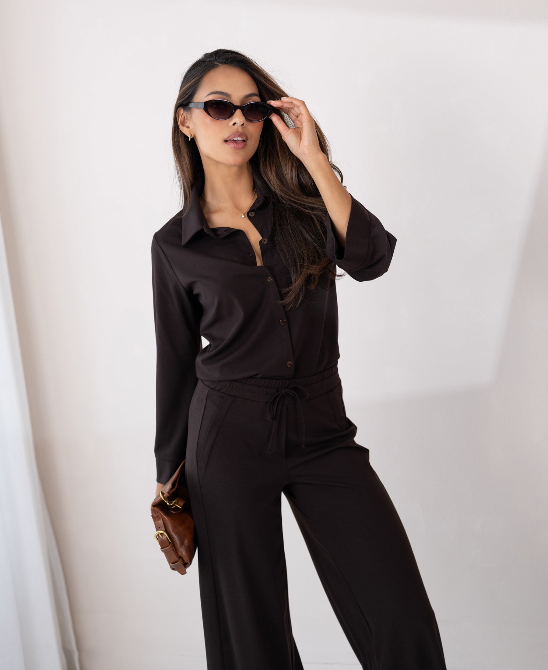 Woman wears brown PLEIN PUBLIQUE LA JULIA travel pants.