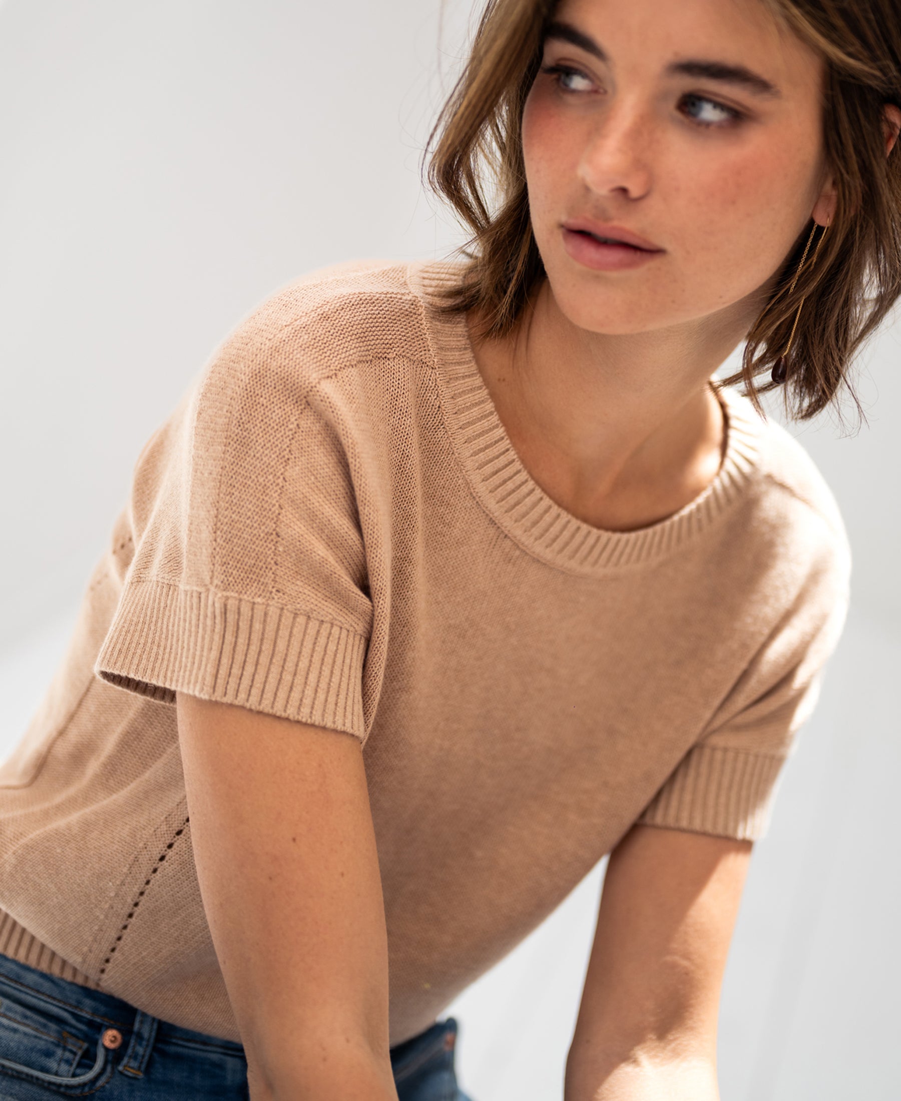Linen blend summer sweater in soft camel, shown from the side in soft light.