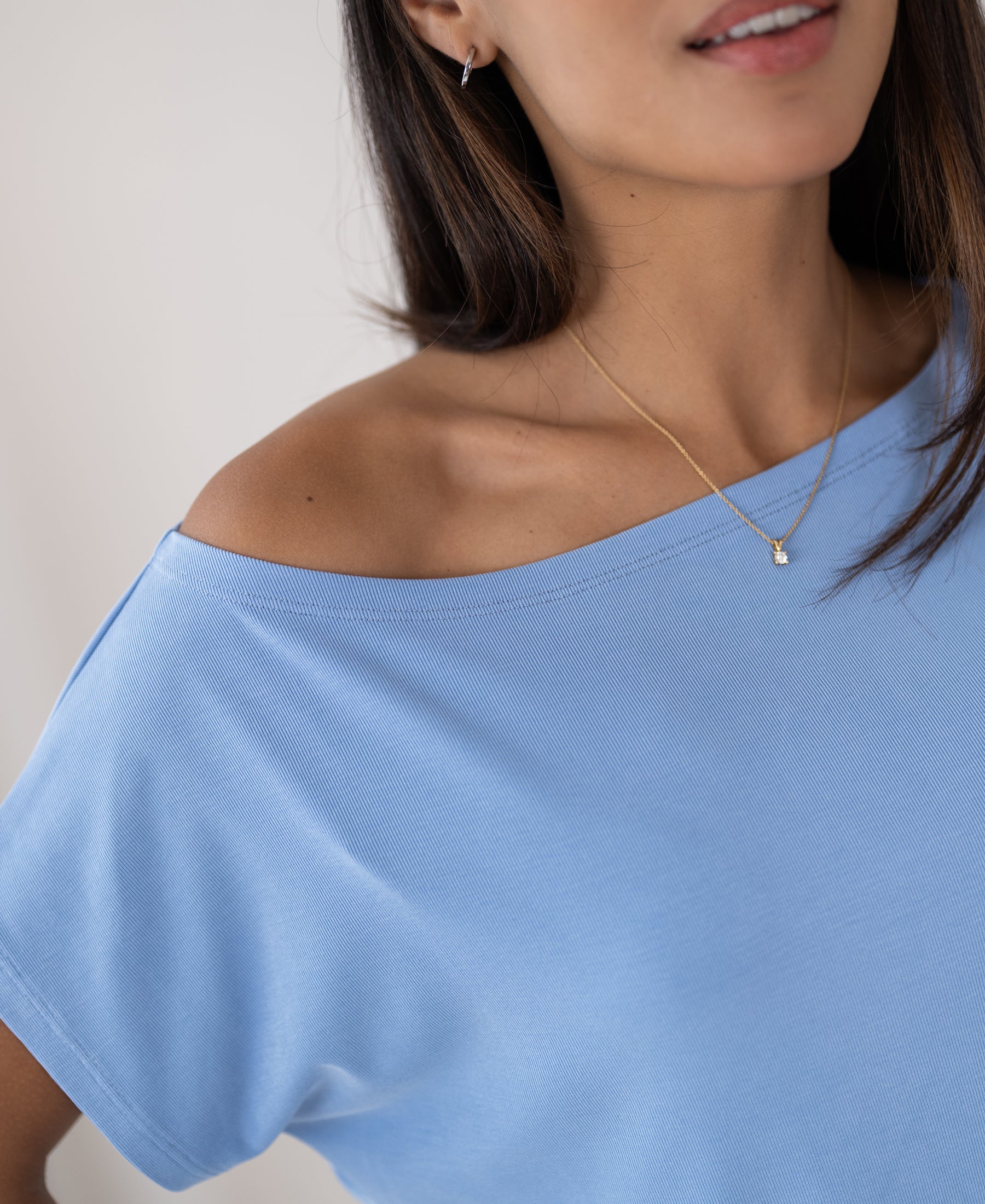Light blue ribbed boat neck T-shirt, cropped at the chin.