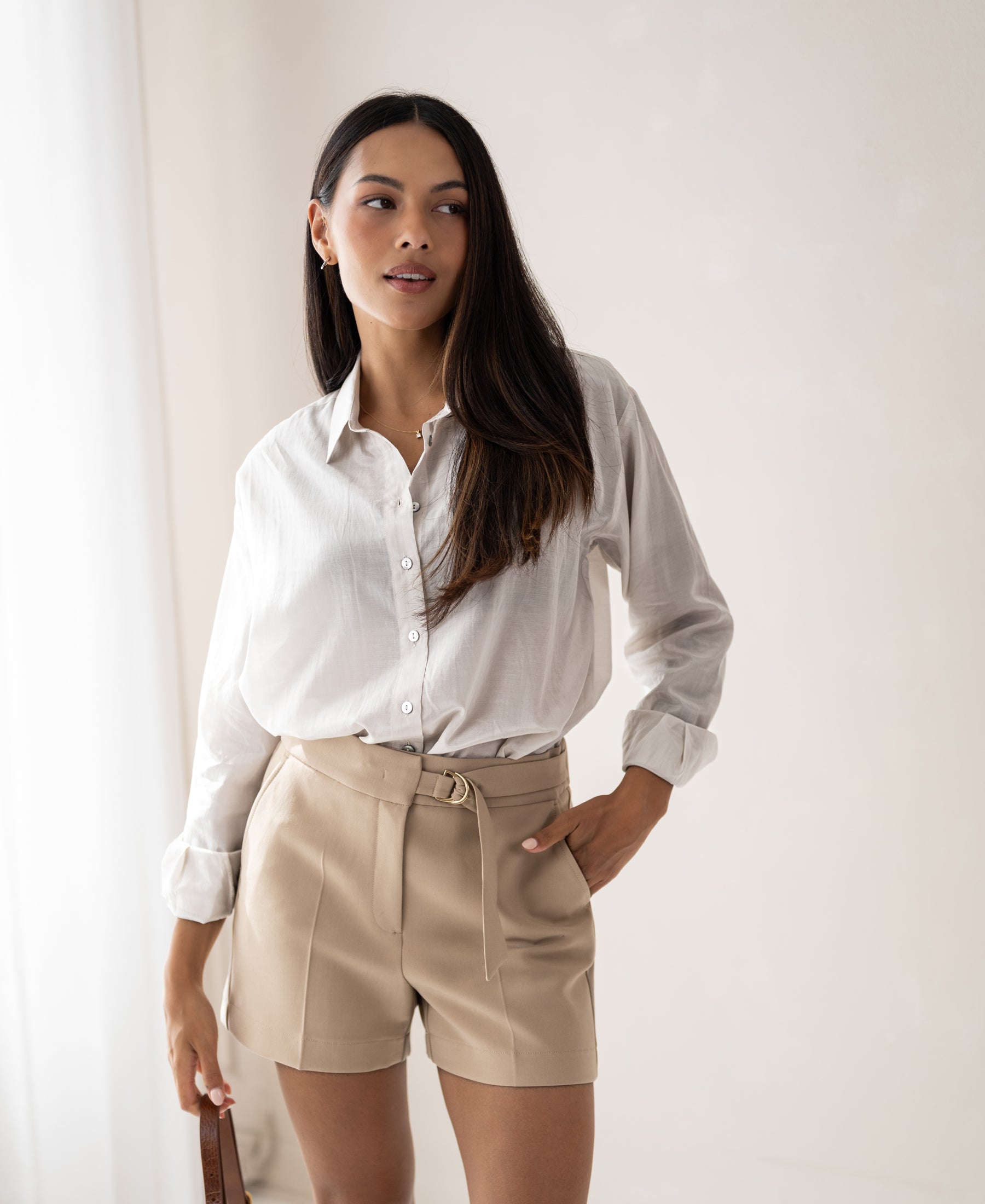 Woman wearing the Dunne oversized blouse in LA SOYEUSE fabric, standing in a softly lit room.
