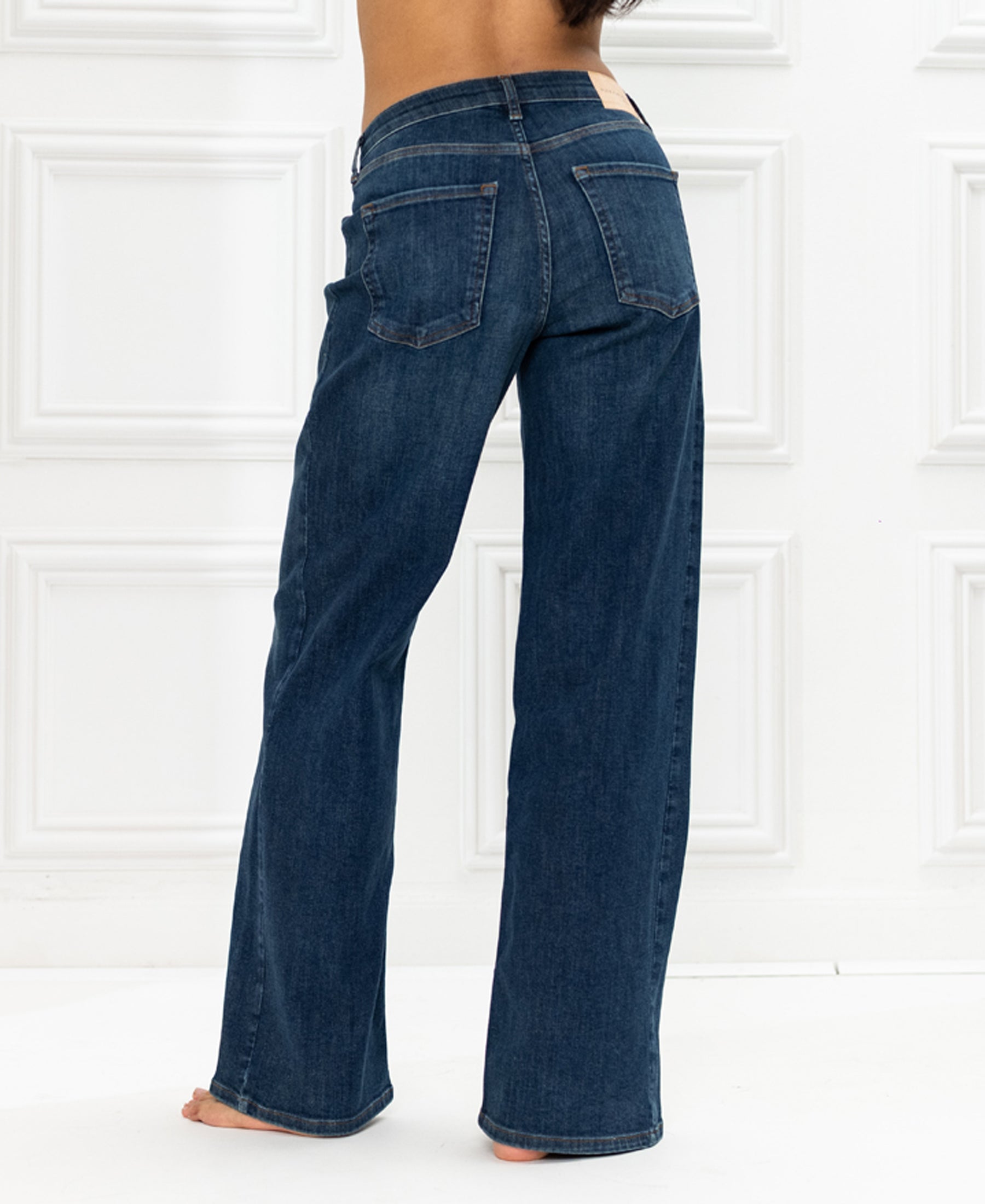 Wide leg blue jeans shown from the back against a white backdrop.