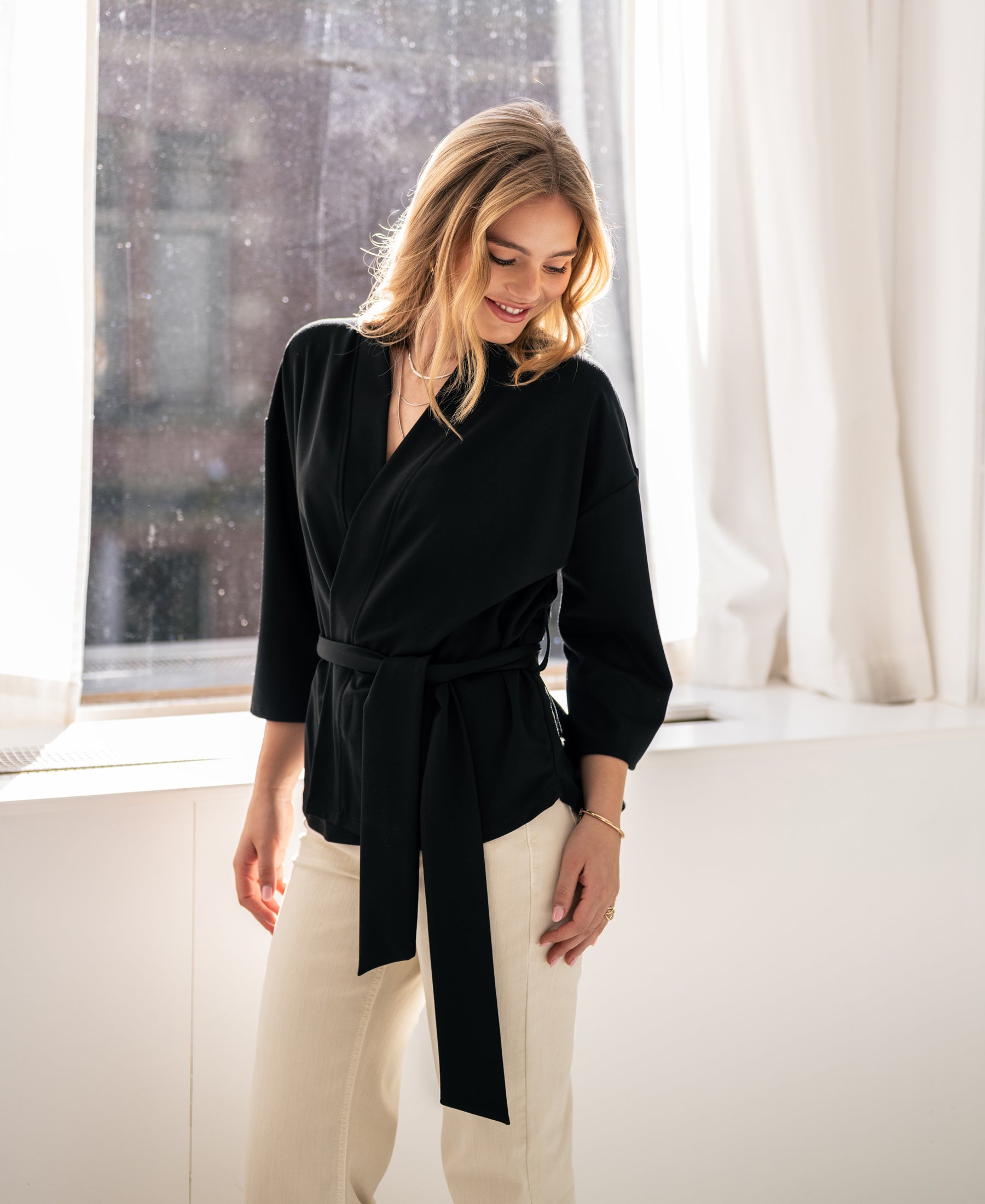 Black PLEIN PUBLIQUE kimono wrap cardigan LA TOKYO displayed in sunlight.