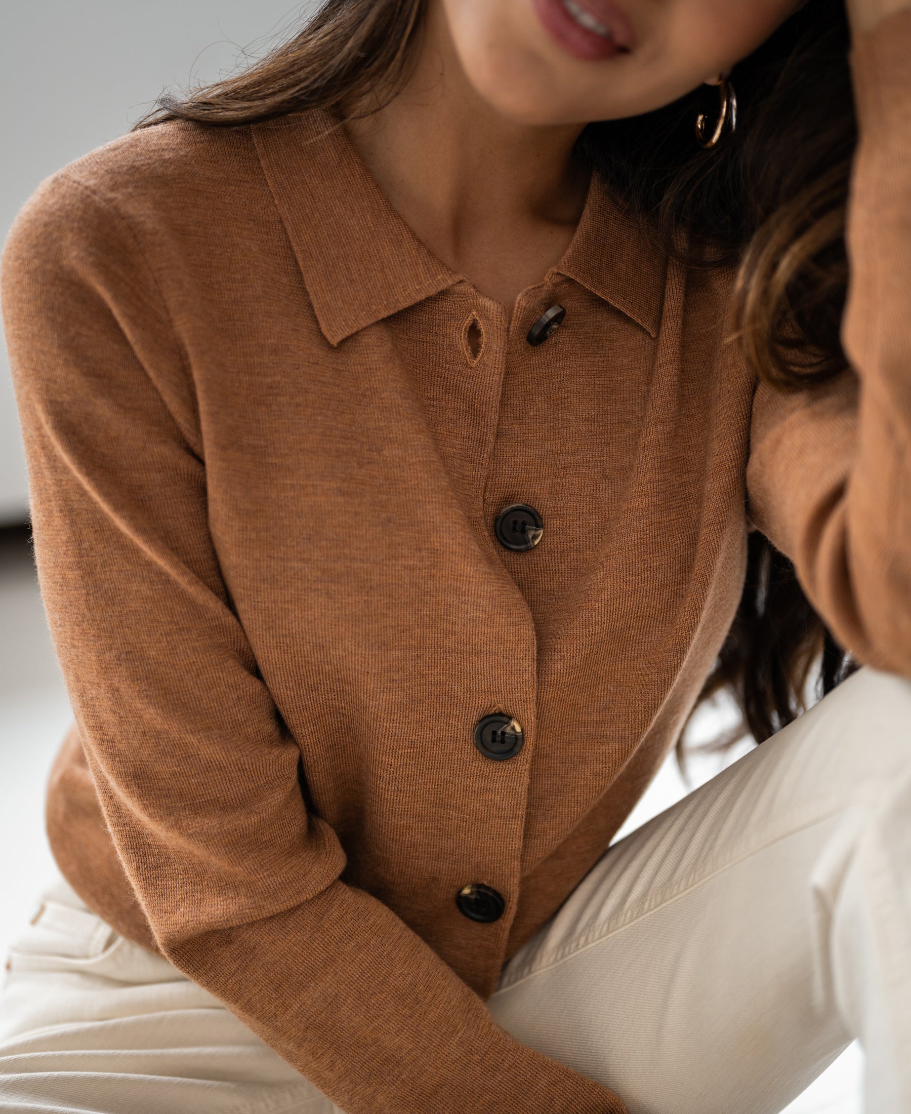 Woman wearing a chai tea-colored Plein Publique collared vest, hand on head, face partly visible.