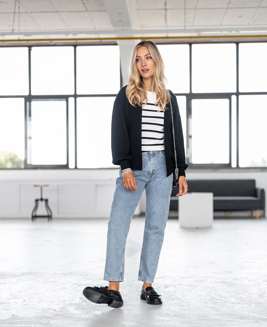 The PLEIN PUBLIQUE Breton sweater L'ELISA in ivory-black, shown worn by a woman in a modern room.