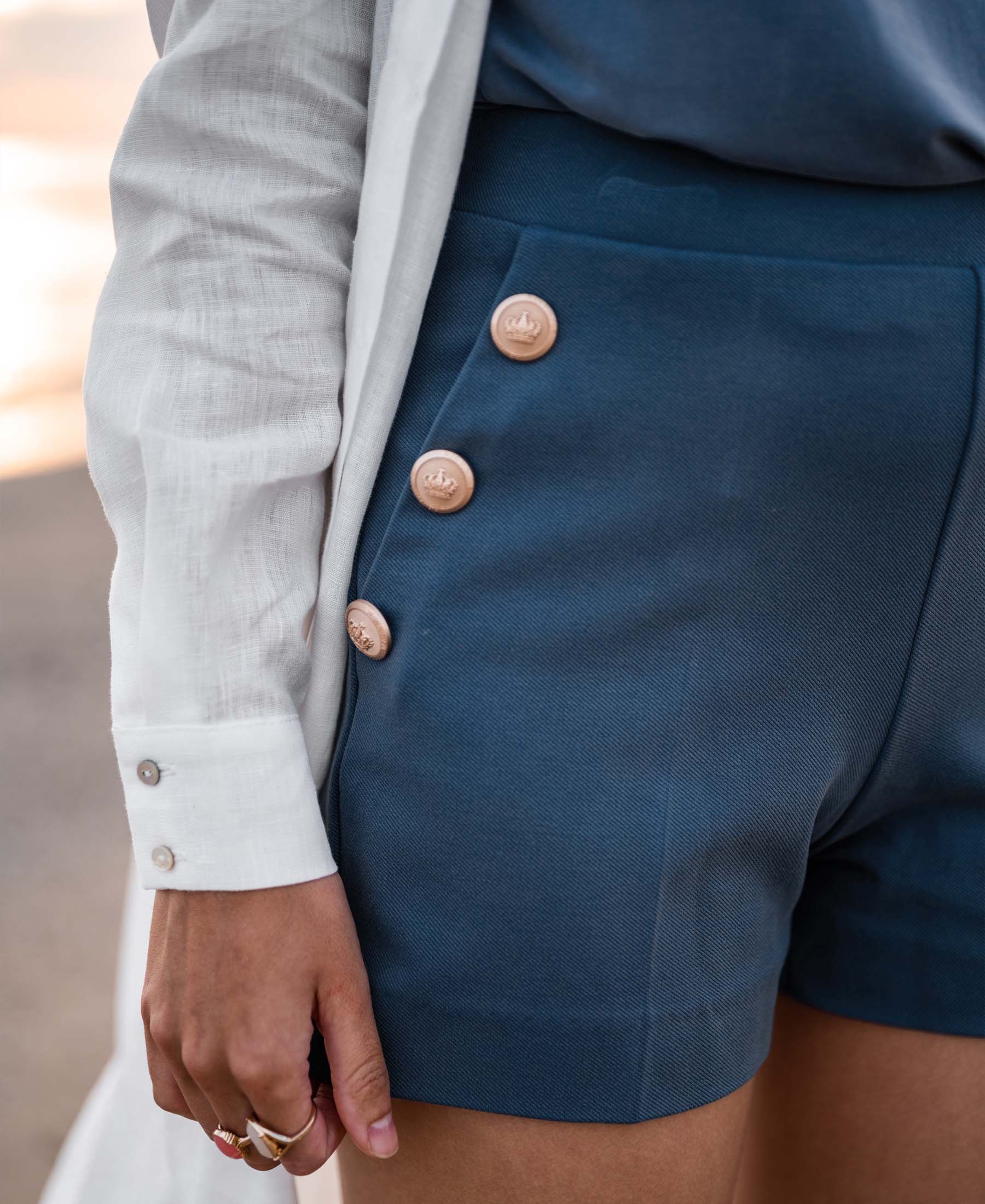 Close-up of blue-gold denim shorts with buttons from Plein Publique, LA PHILLY style.