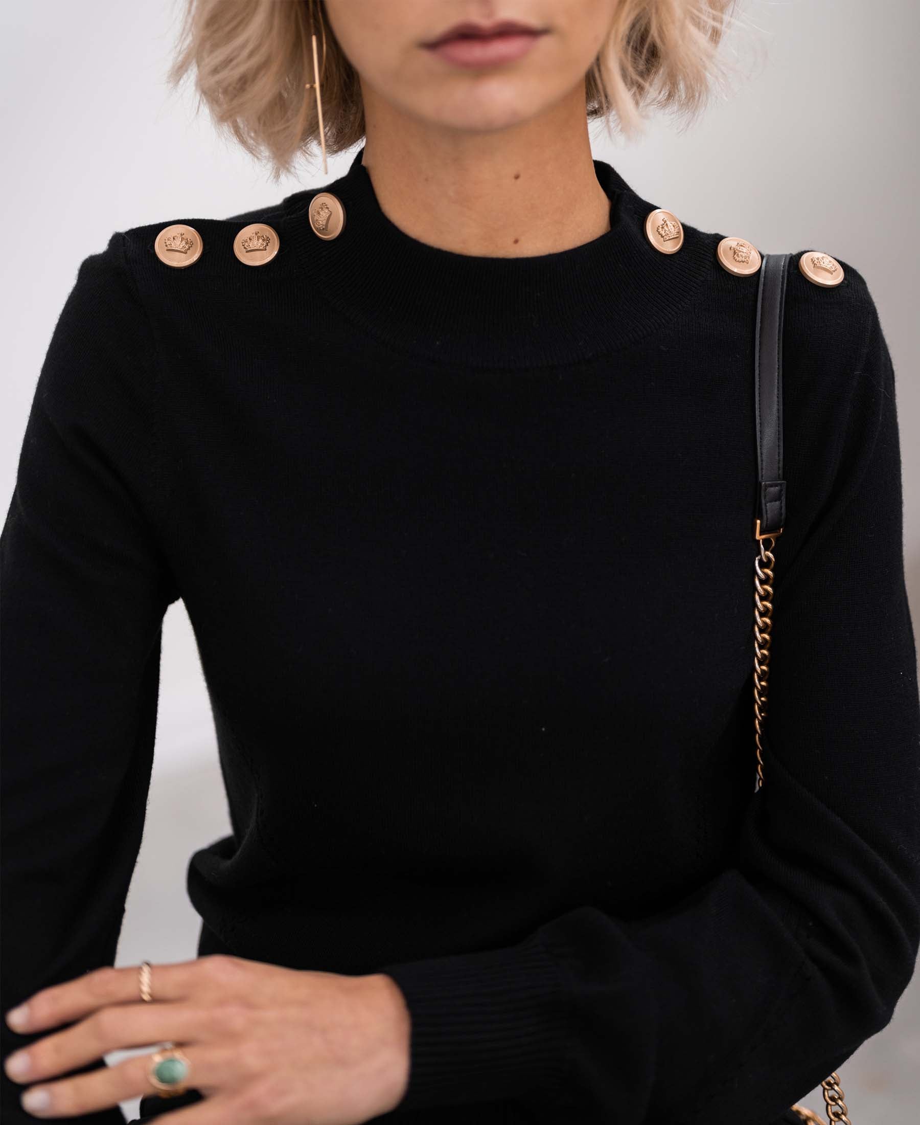 Woman wearing a black and gold merino wool sweater.