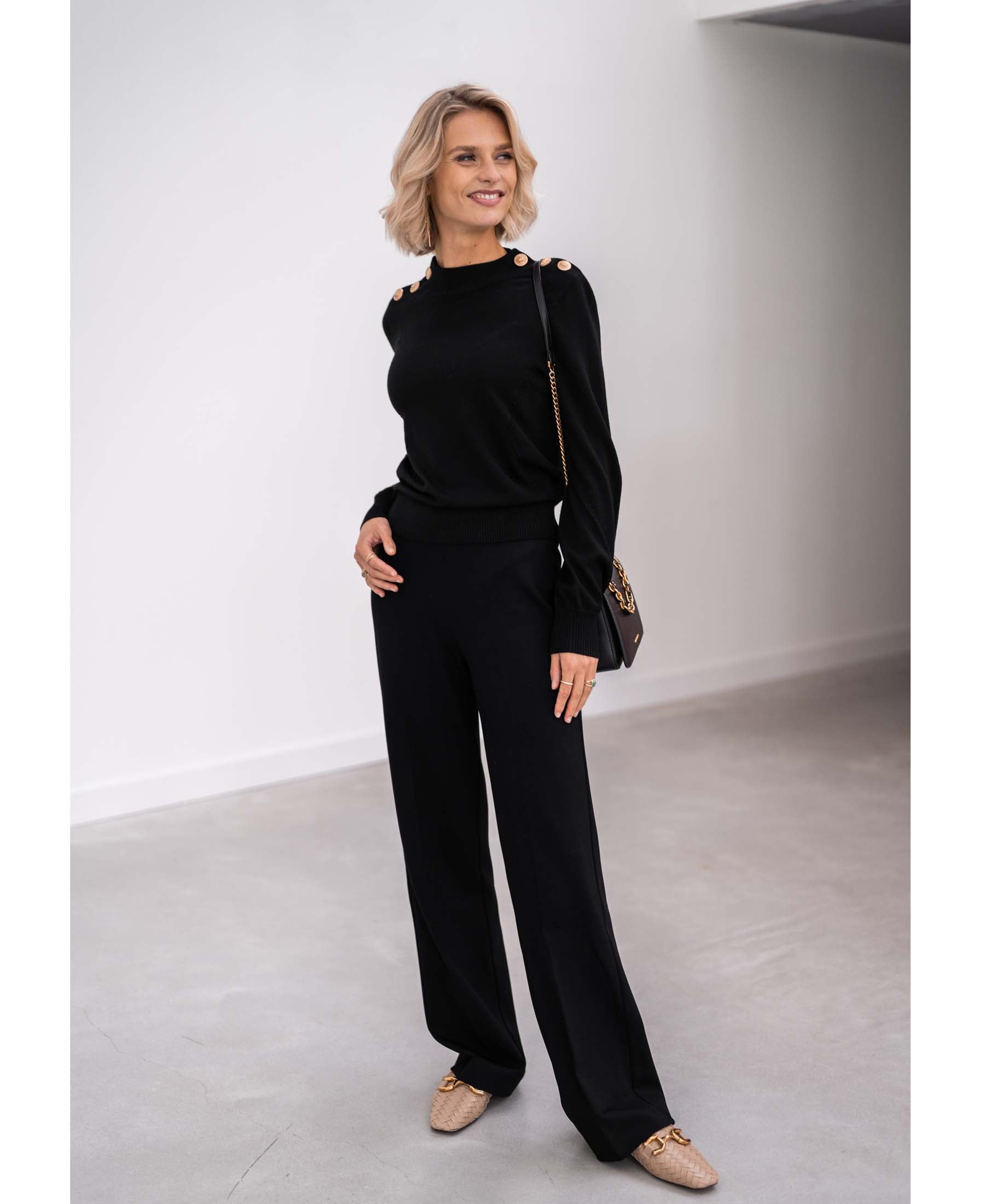 Front view of woman wearing a black and gold merino wool sweater by PLEIN PUBLIQUE.