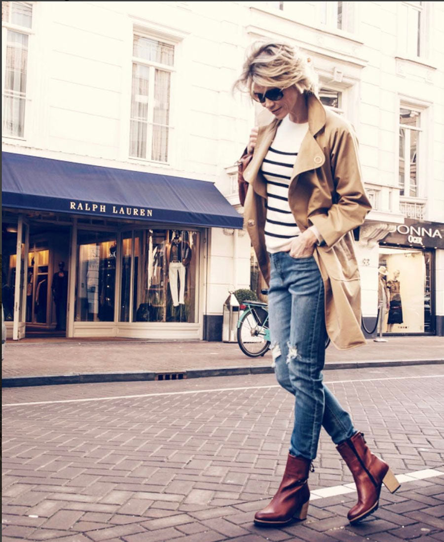 Woman in an ivory-black PLEIN PUBLIQUE Breton-style sweater walks by a Ralph Lauren store.