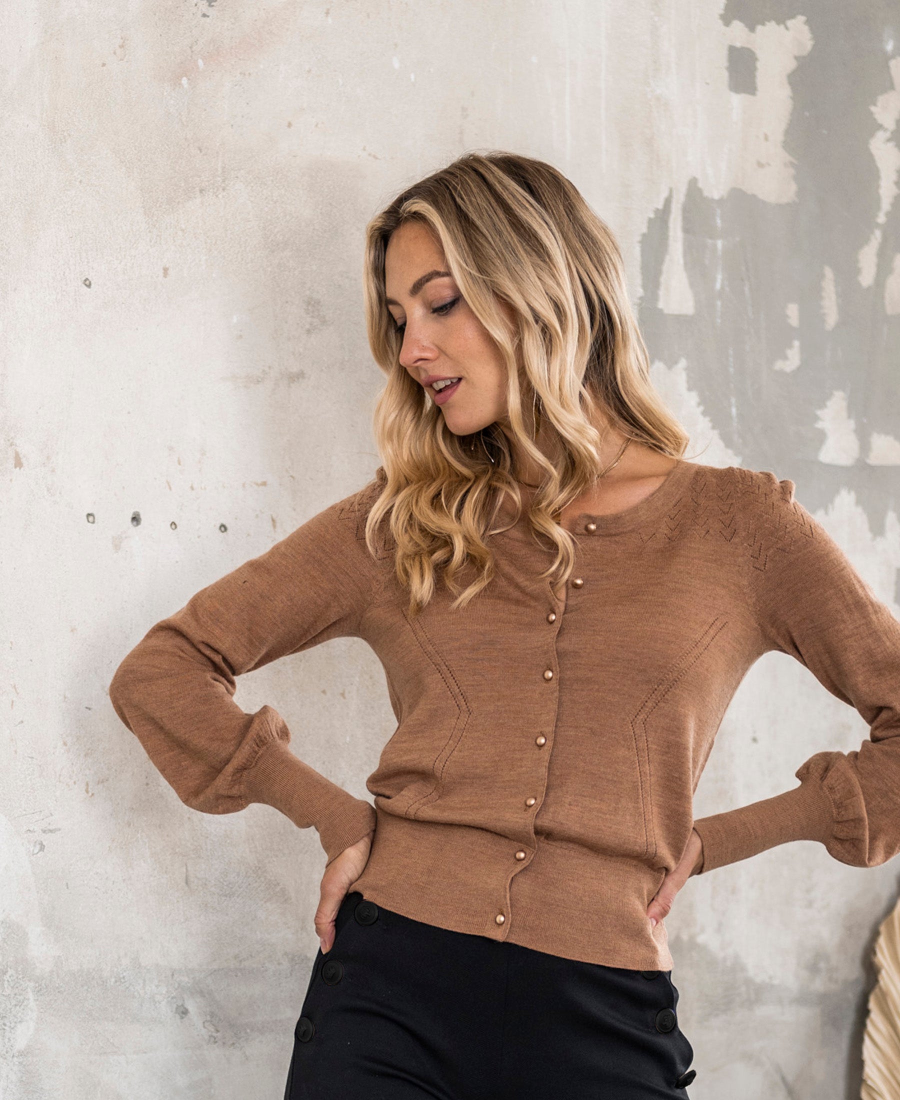 PLEIN PUBLIQUE LA FRAGANCE Cardigan in Chai Tea and Gold, shown on model by a textured wall.