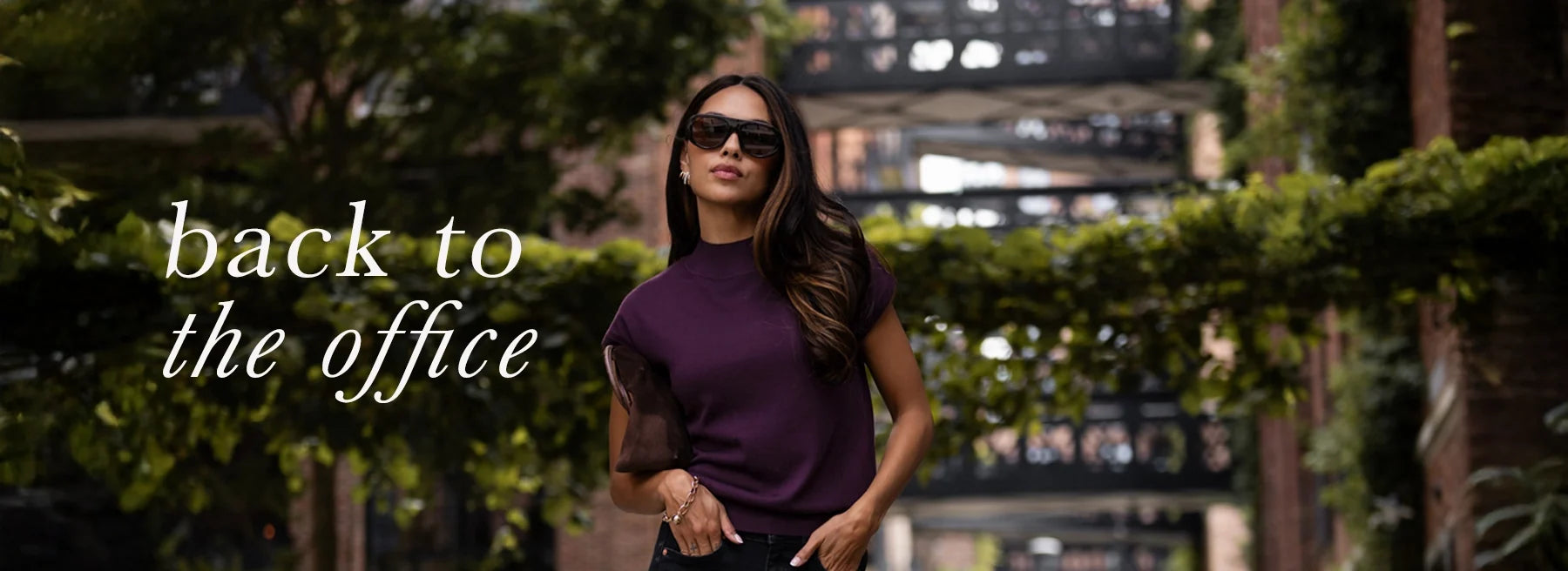 Woman wearing plum Merino wool collared top, seen outdoors on a city walkway.