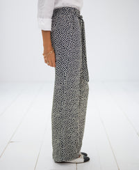 Side view of charcoal and ivory polka dot trousers on white floor.