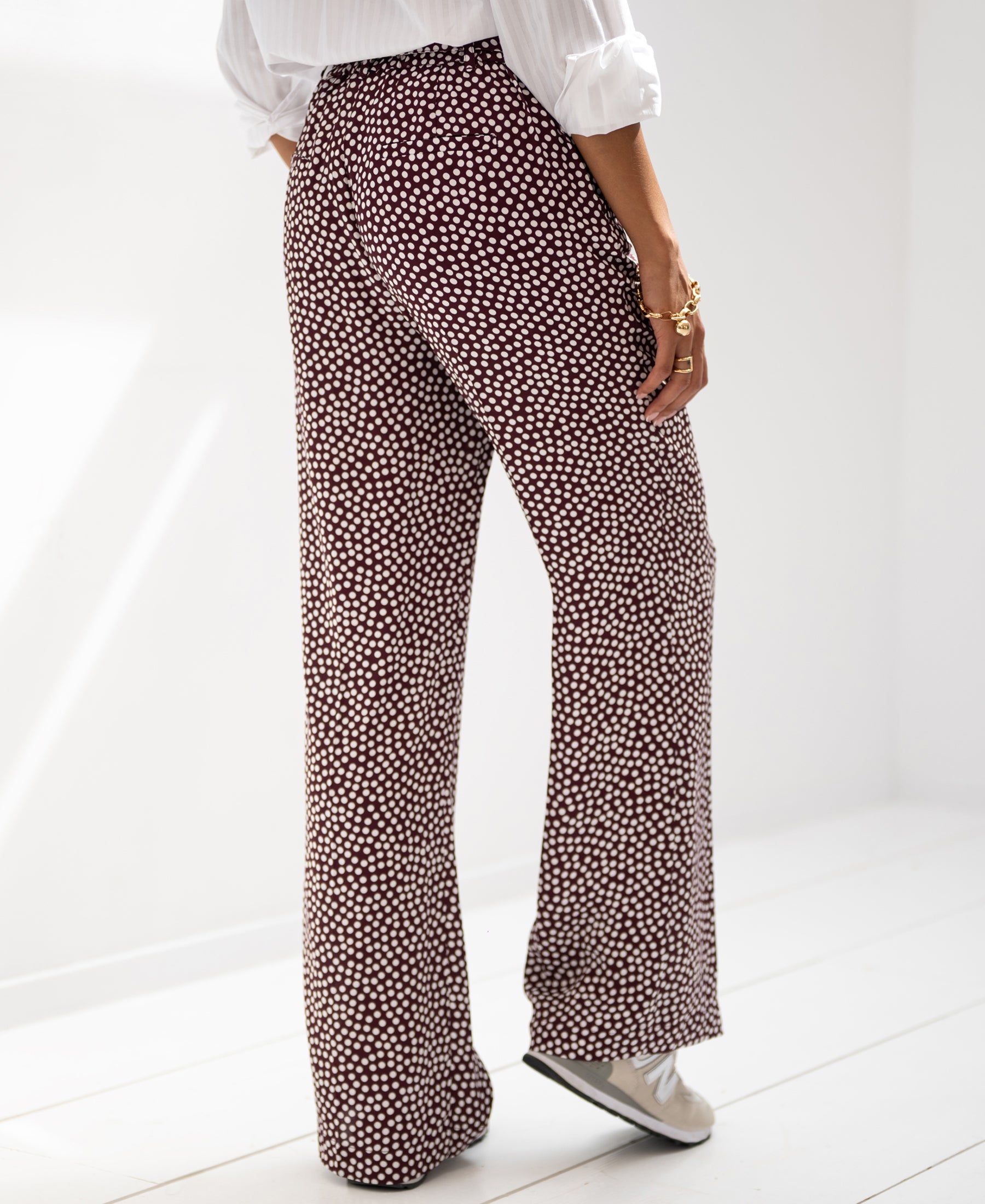 Woman’s polka dot pants in wine and ivory, shown indoors.