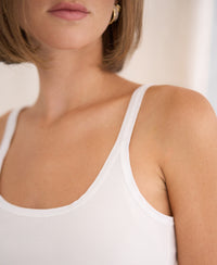 Woman wears ivory Luxe Cami top in satin by PLEIN PUBLIQUE.