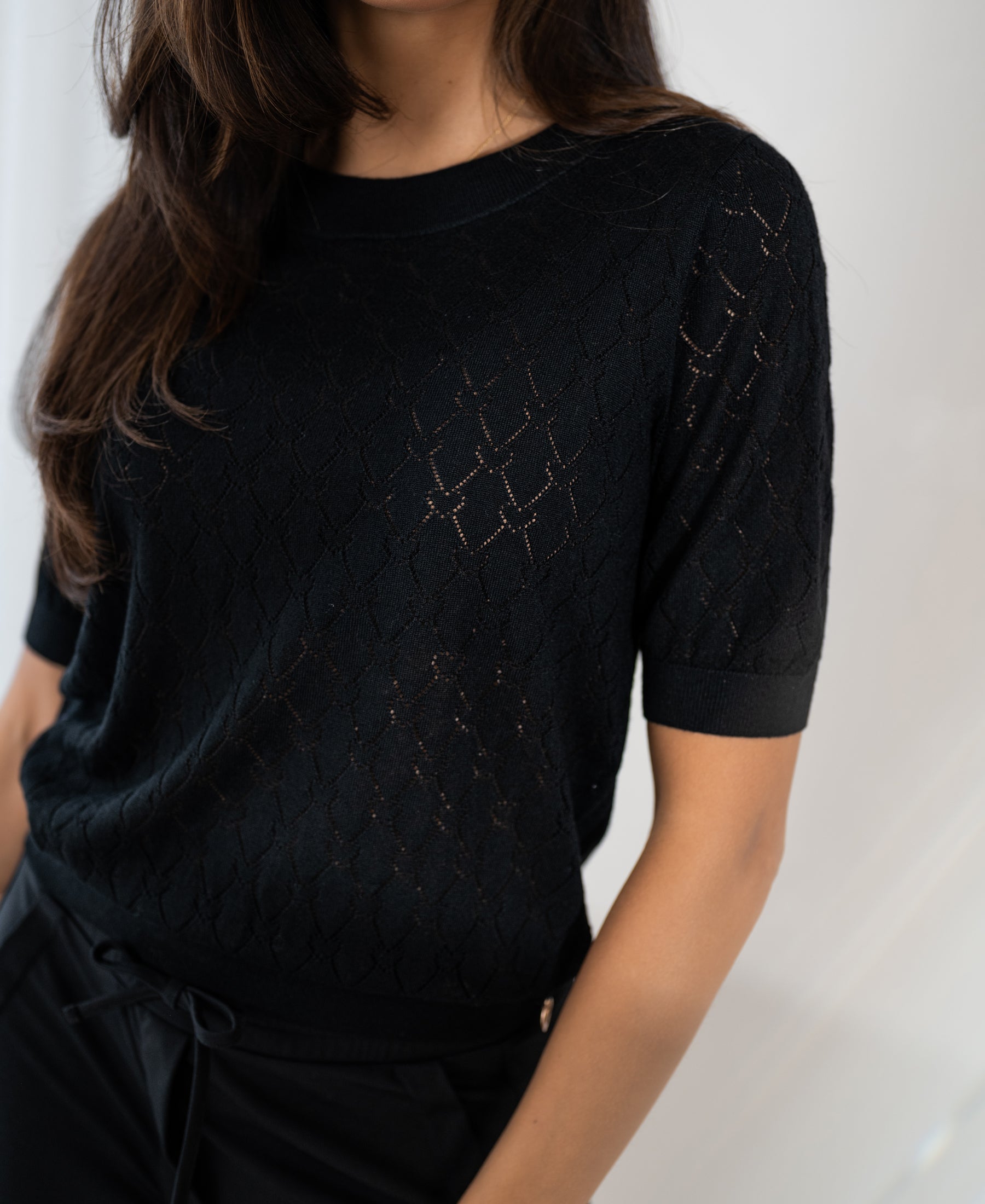 Black PLEIN PUBLIQUE sweater with heart pattern, shown from shoulders to hips against a light background.