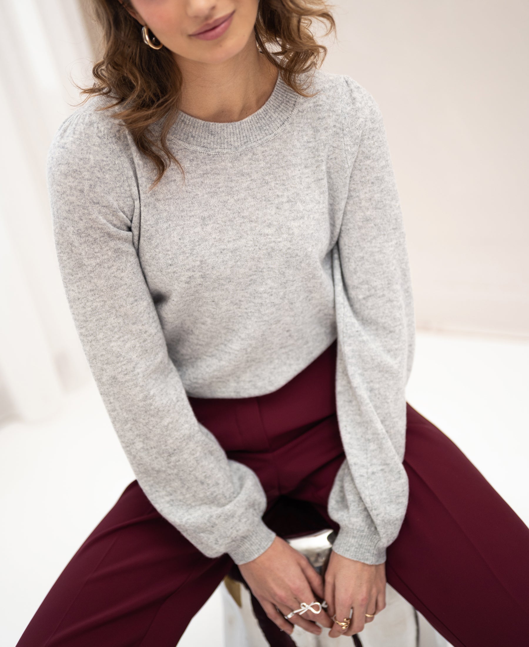 Light grey melange merino wool sweater in a bright minimal setting.