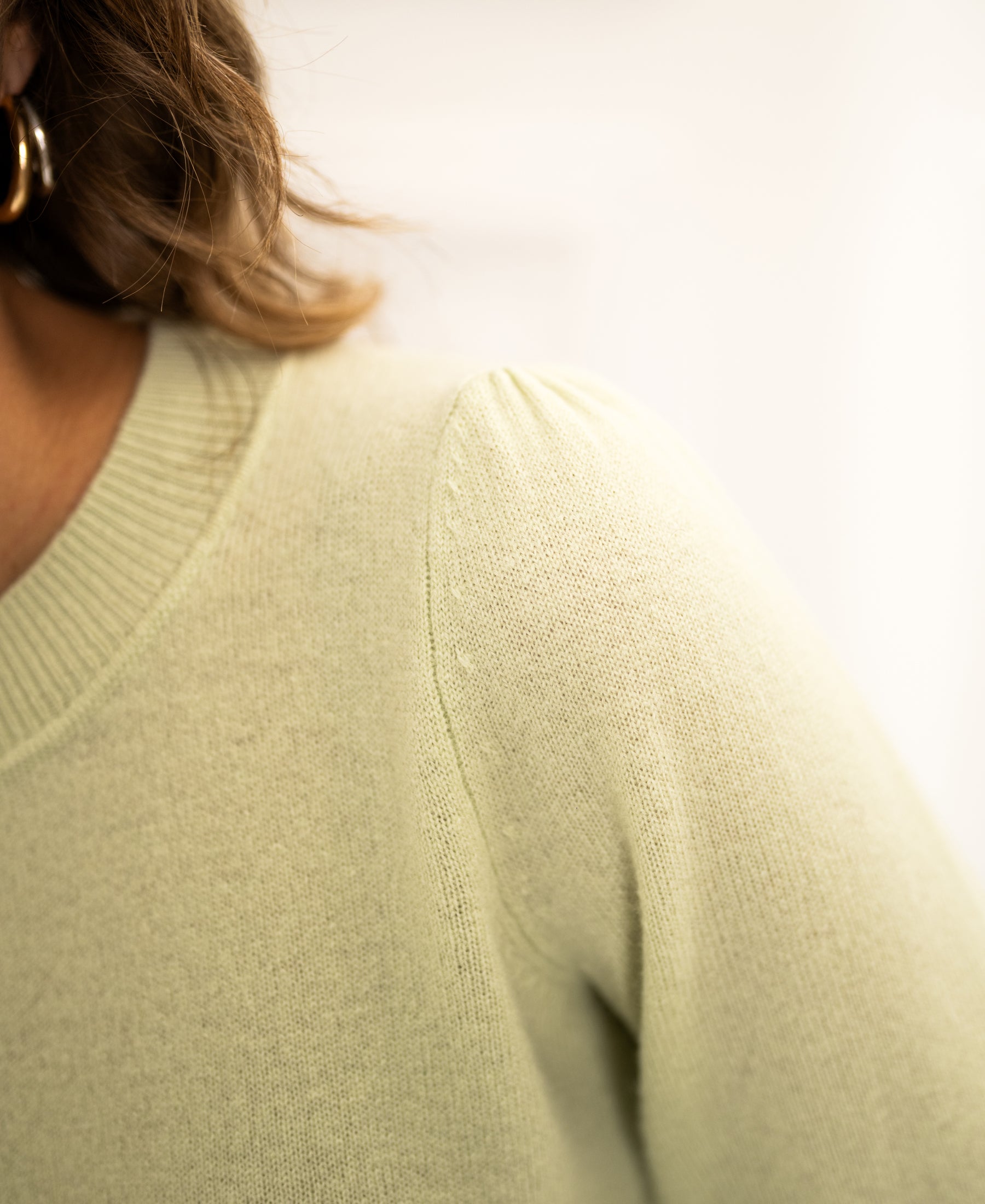 Close-up of the Plein Publique soft merino sweater LA BAYONNE in light green with puffed sleeves and a ribbed collar.