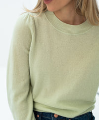 Light green merino wool sweater shown from the shoulders down.