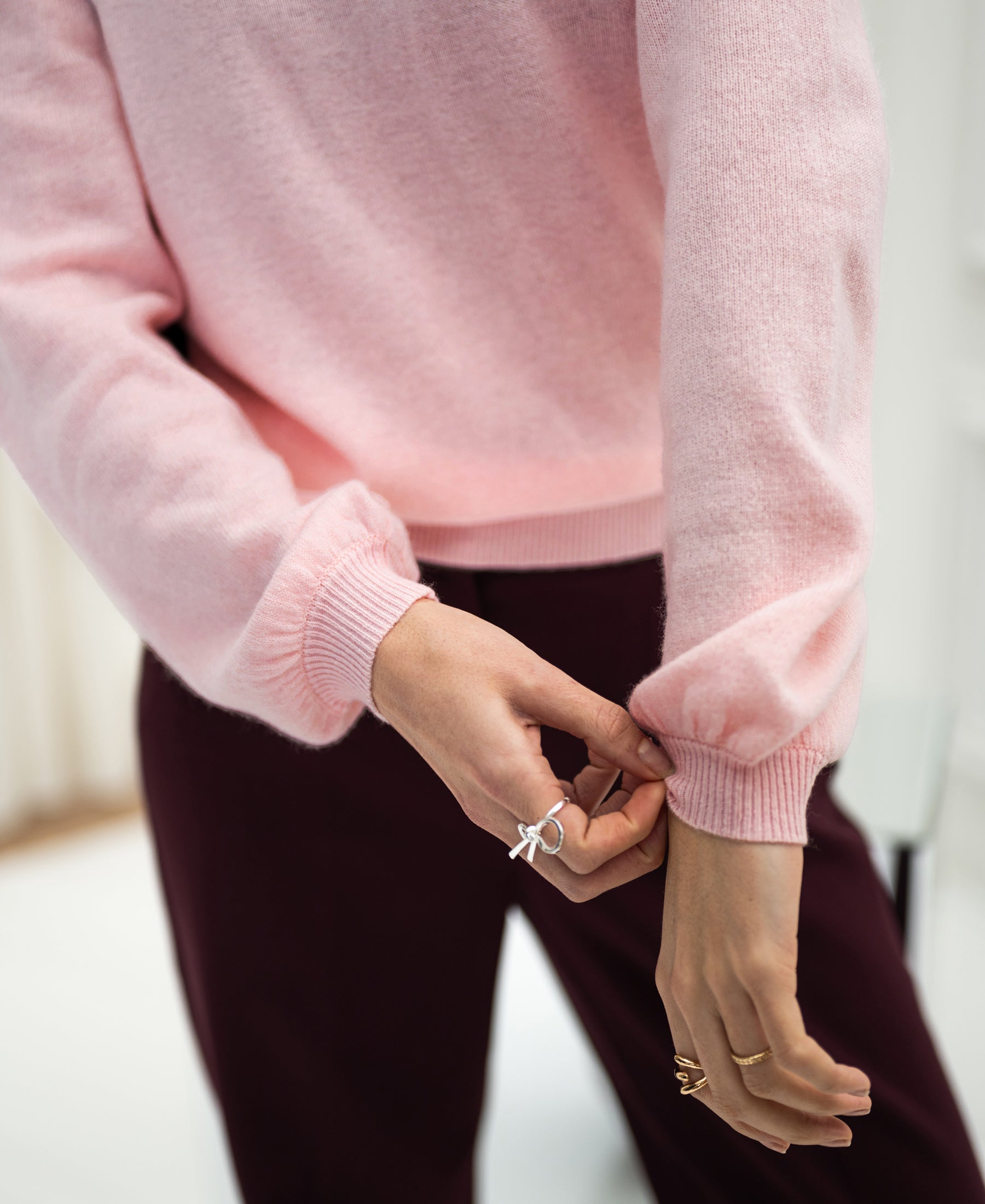 Light pink merino wool sweater with soft texture, shown with a sleeve being adjusted.
