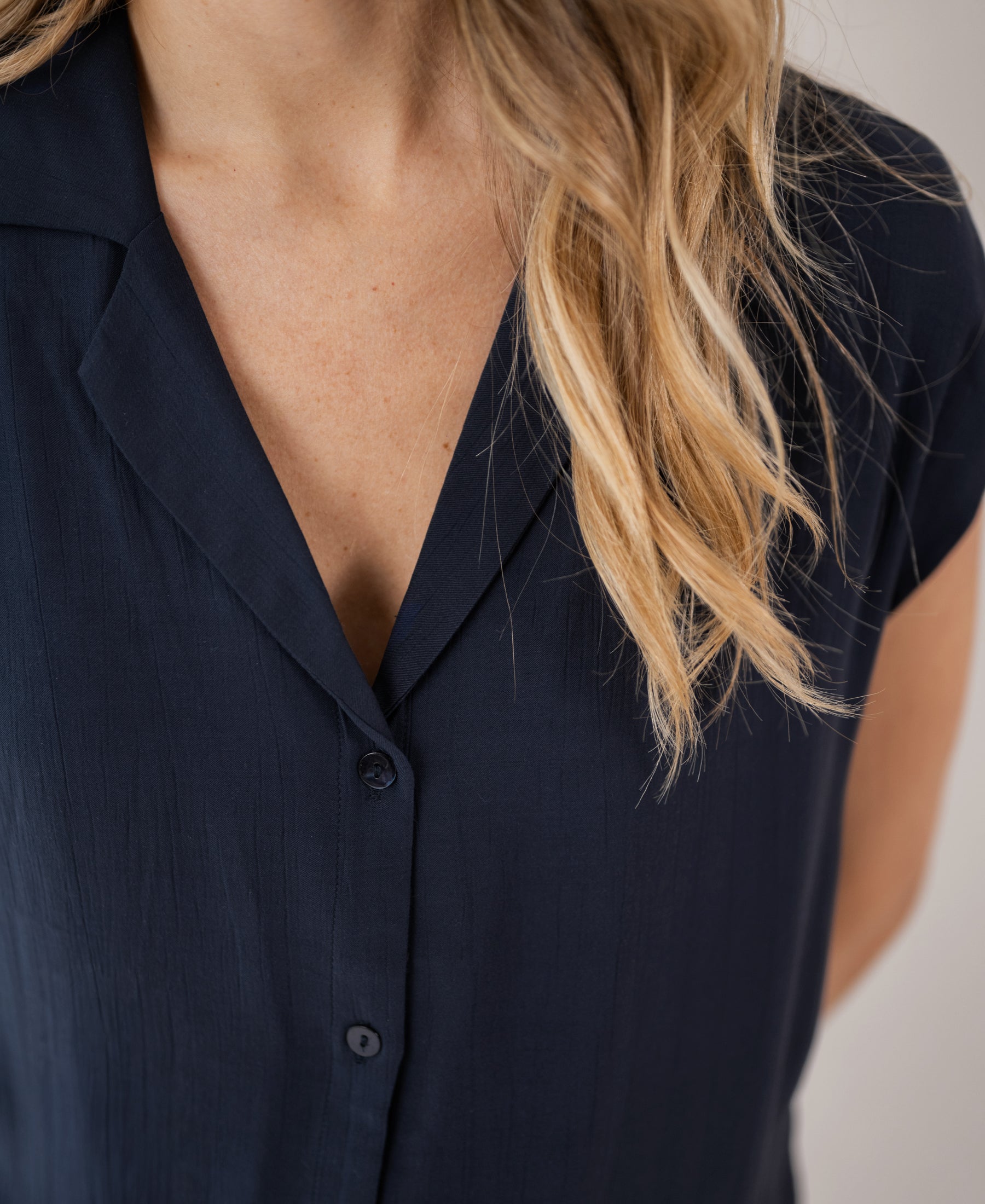 Sleeveless dark blue blouse shown from neck to mid-torso.