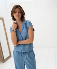 Sleeveless blouse in jeans blue by PLEIN PUBLIQUE, shown indoors.