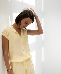 Sleeveless blouse LA BIJOU soft yellow by PLEIN PUBLIQUE shown in soft sunlight against a white wall.