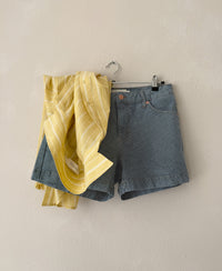 Yellow striped shirt hanging on a wall with a hanger and clip.