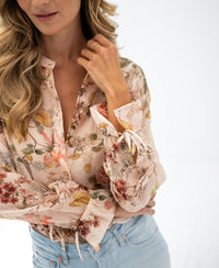 Woman wearing a blush floral print blouse.