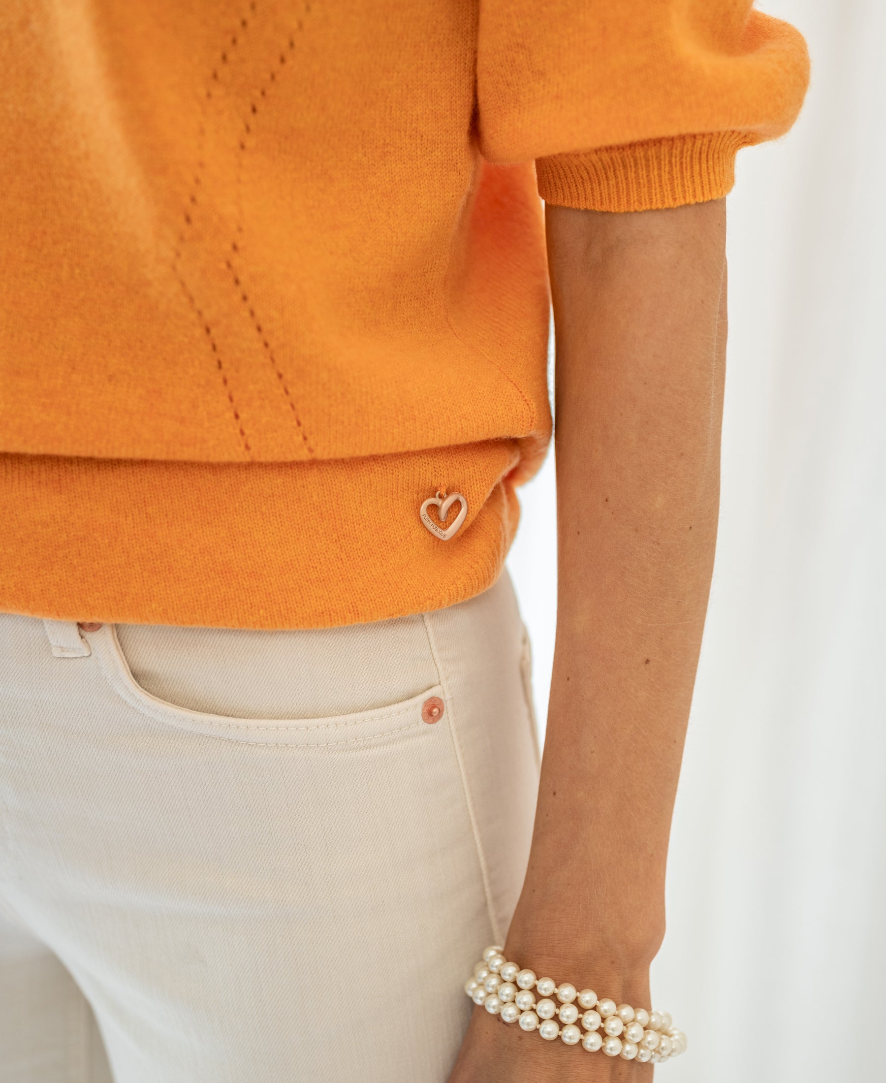 Person wearing an orange PLEIN PUBLIQUE LA BLANCHE sweater.