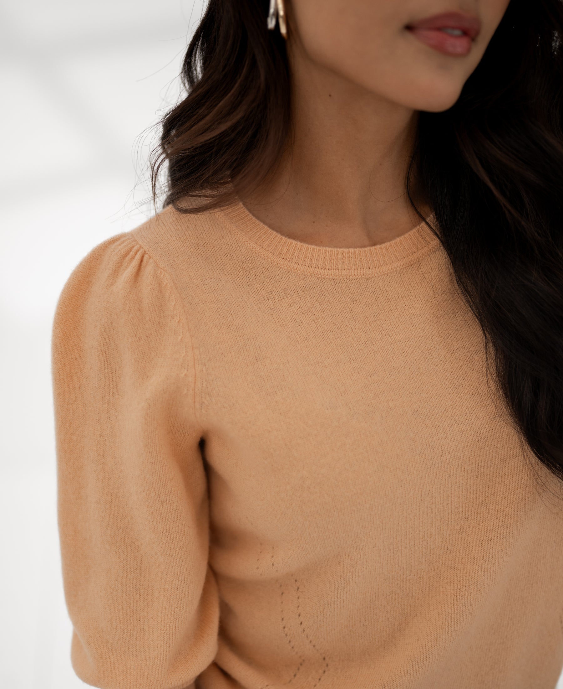 Soft salmon-colored knit sweater, shoulders up view.