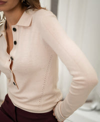 Woman wearing a Plein Publique merino wool polo shirt in butter blush, shown from shoulders to hips.