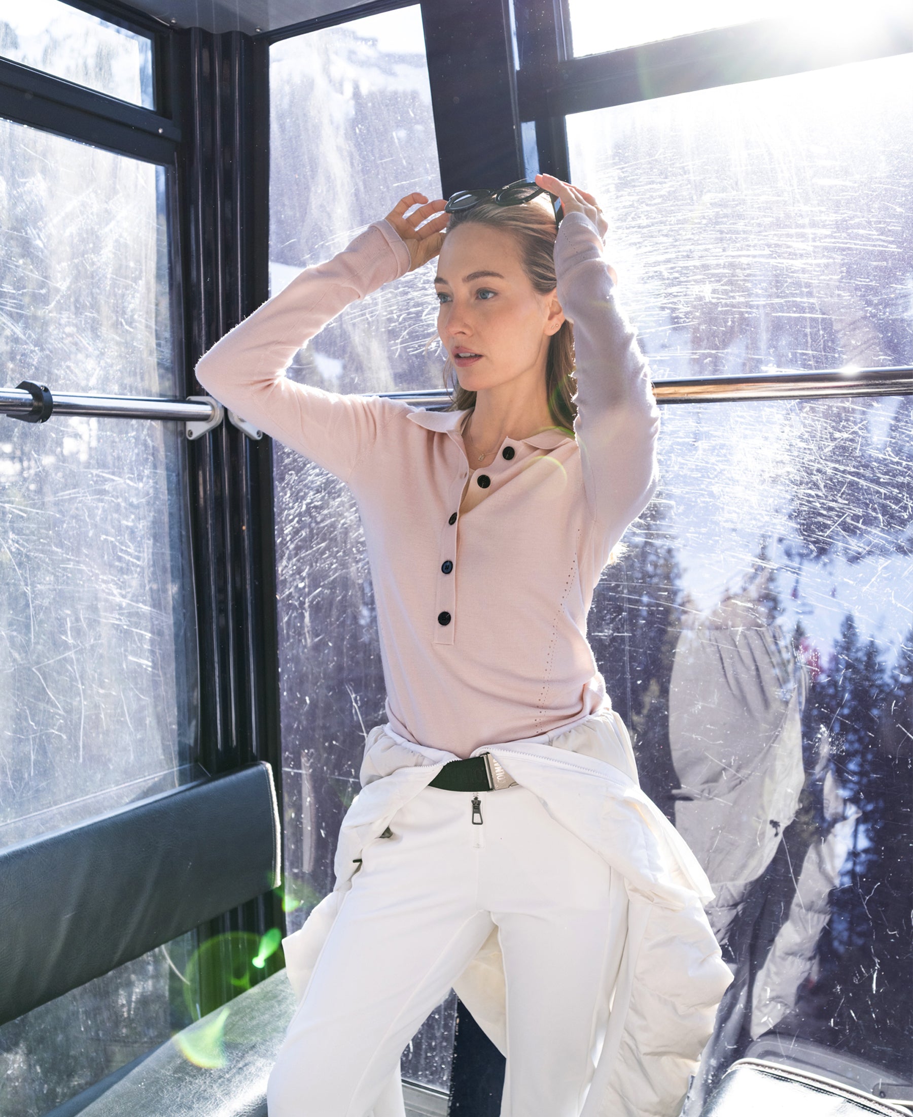 Woman wearing PLEIN PUBLIQUE LE BOBIGNY butter blush merino wool polo in sunlit cable car.