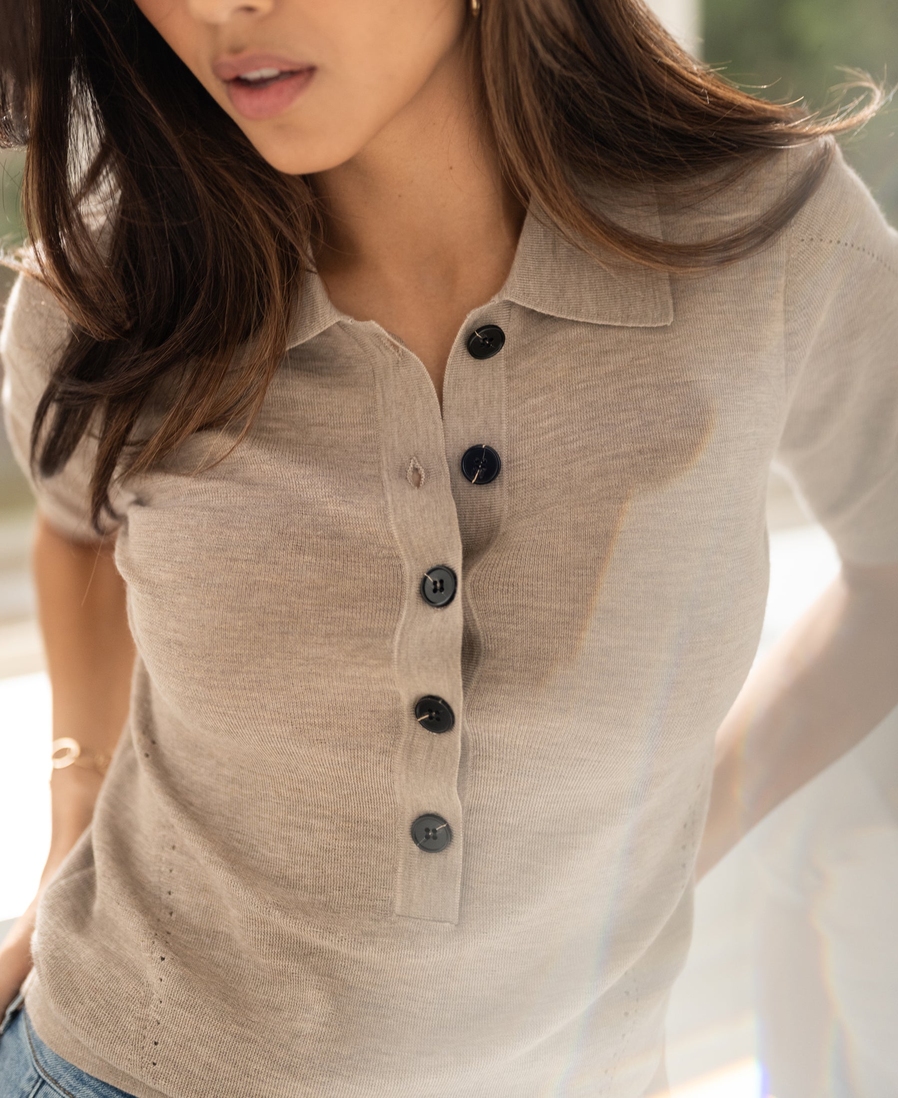 Woman wearing a PLEIN PUBLIQUE merino wool polo shirt in dark sand, an all-season classic.