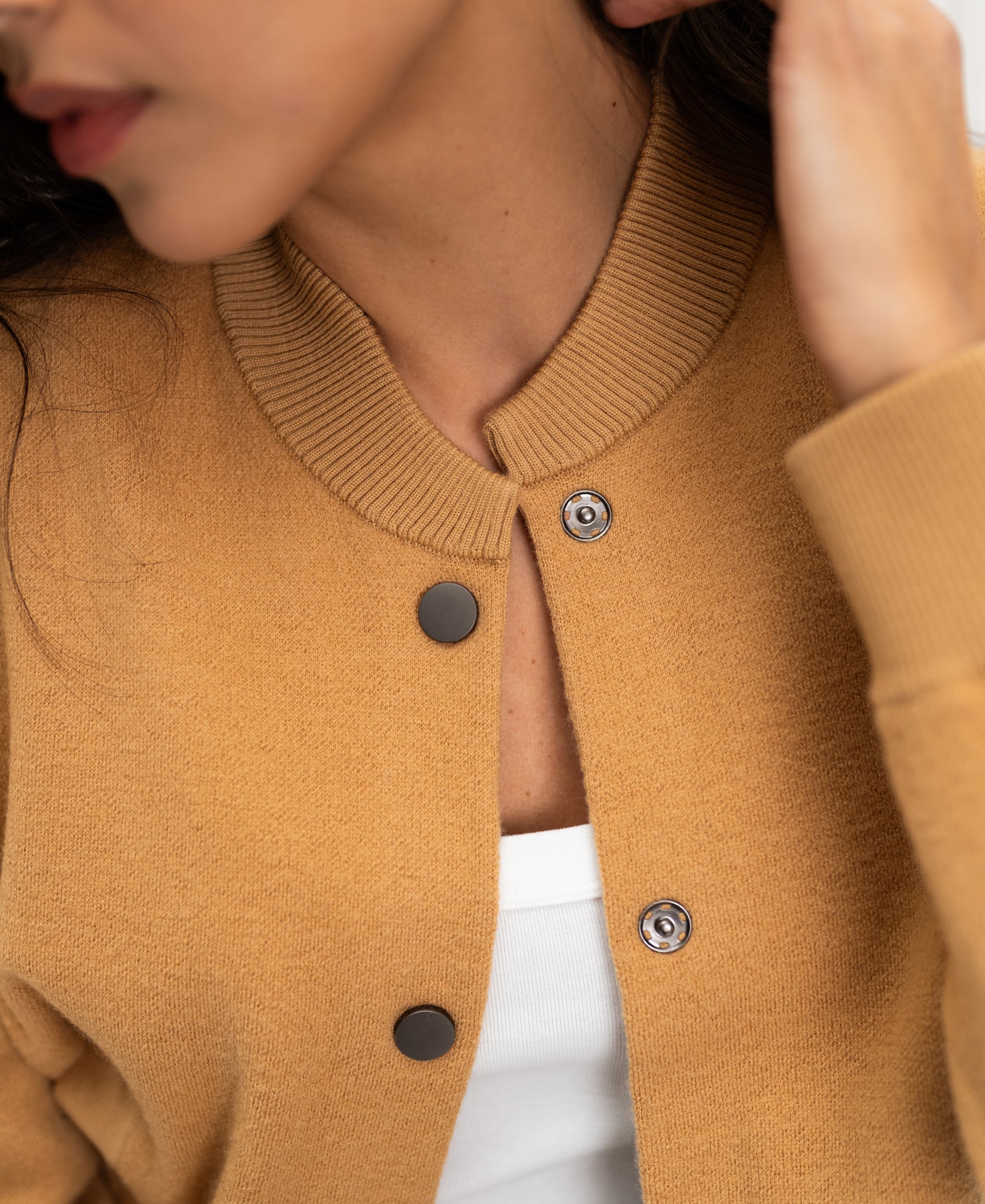 Close-up of the LA BOMBA light camel bomber jacket in a soft material, shown worn, with focus on color and fabric texture.