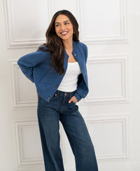 Women's bomber jacket in jeans blue from Plein Publique, displayed in front of a white paneled wall.