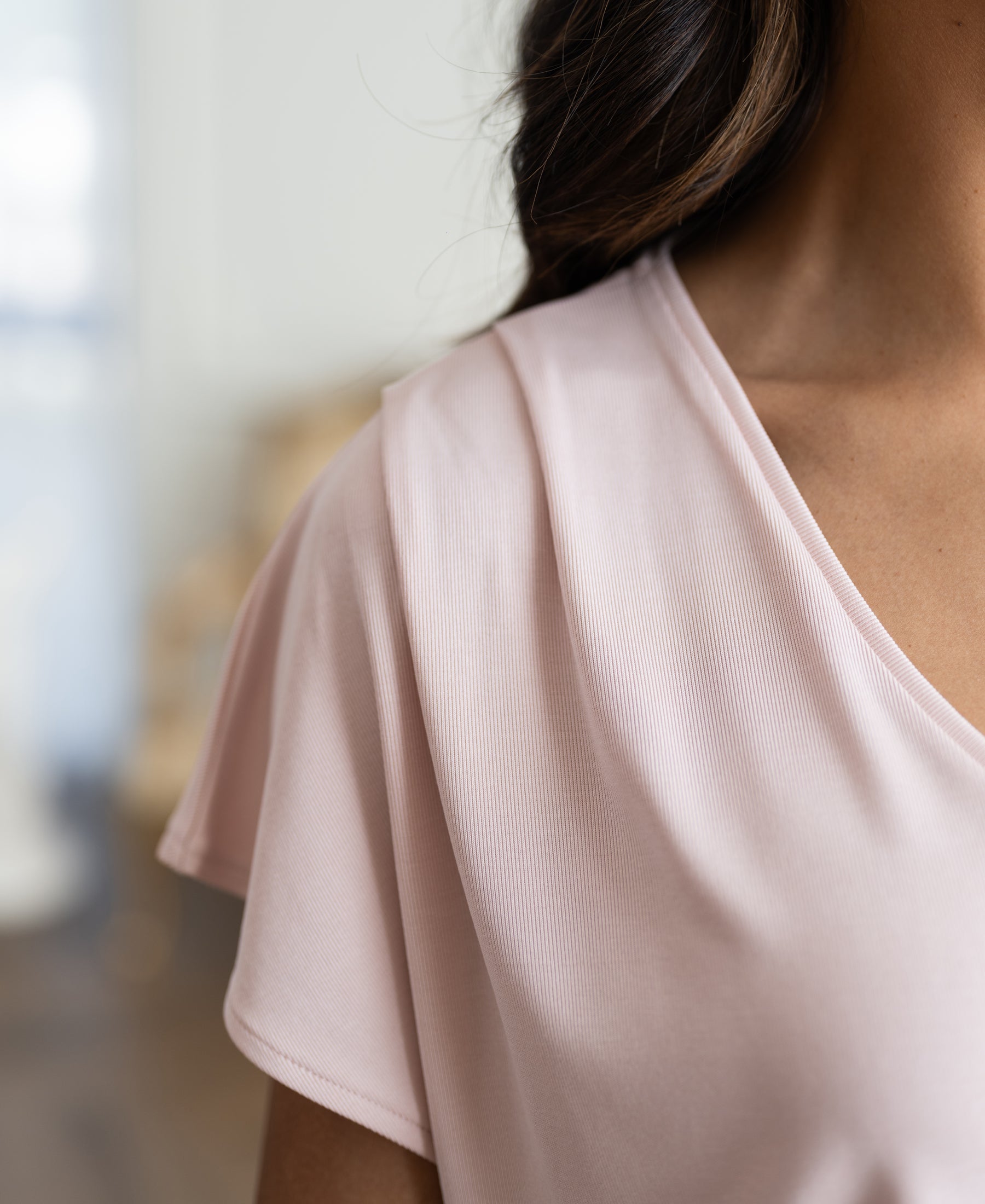 Blush pink ribbed T-shirt in soft indoor lighting, shown from shoulders down.