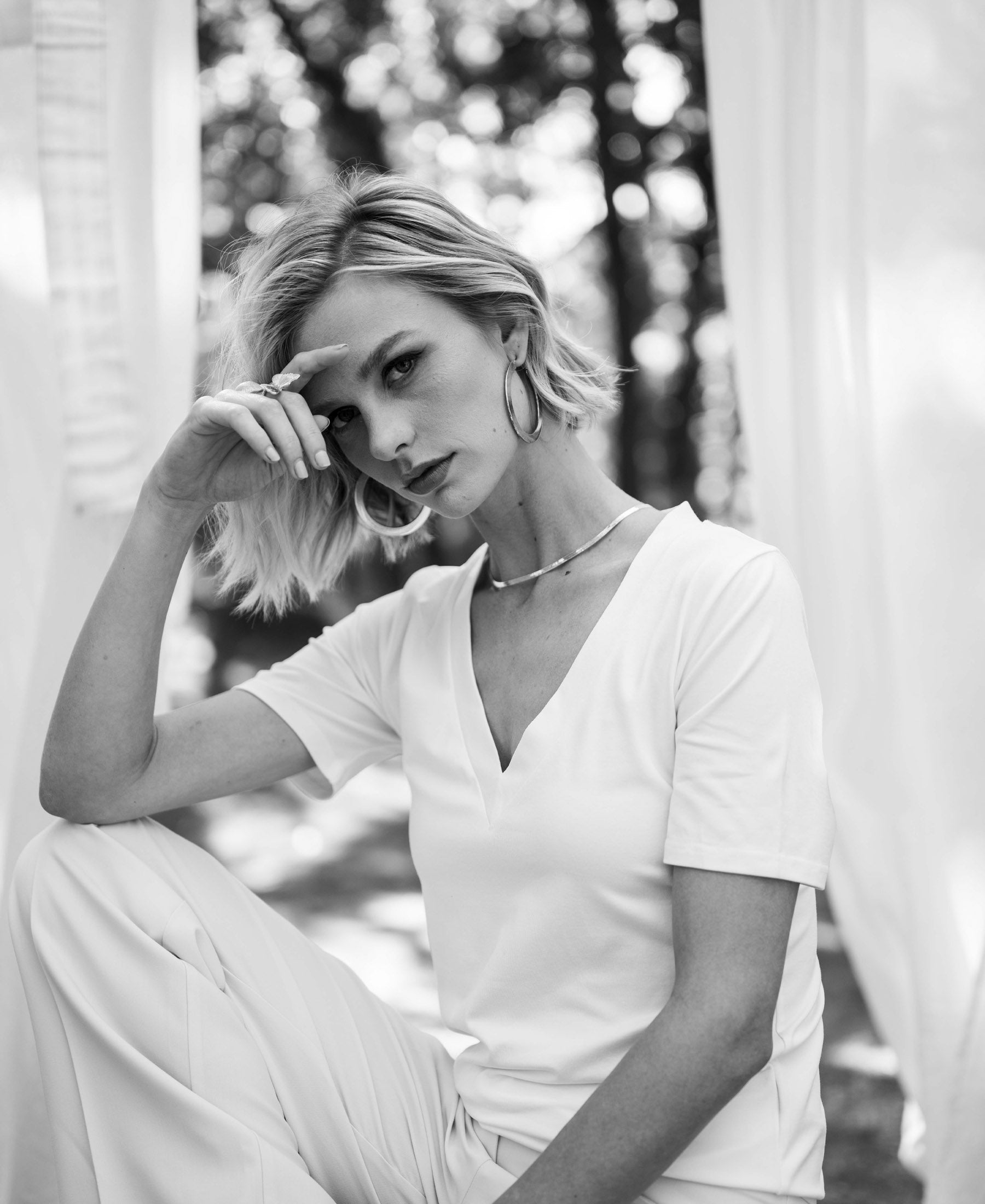 Black and white photo of a woman wearing a Plein Publique LA VIDA white V-neck T-shirt.