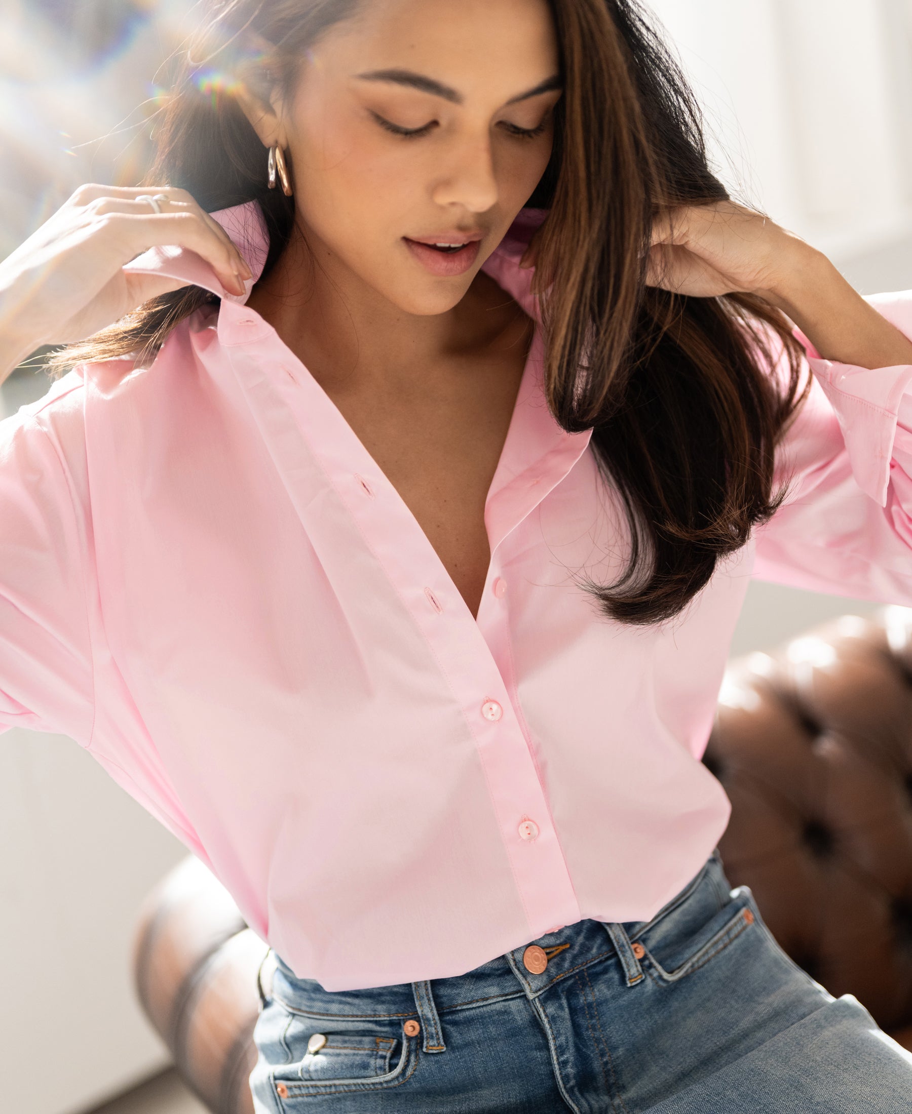 Light pink oversized blouse, collar being adjusted, shown with sunlight behind.