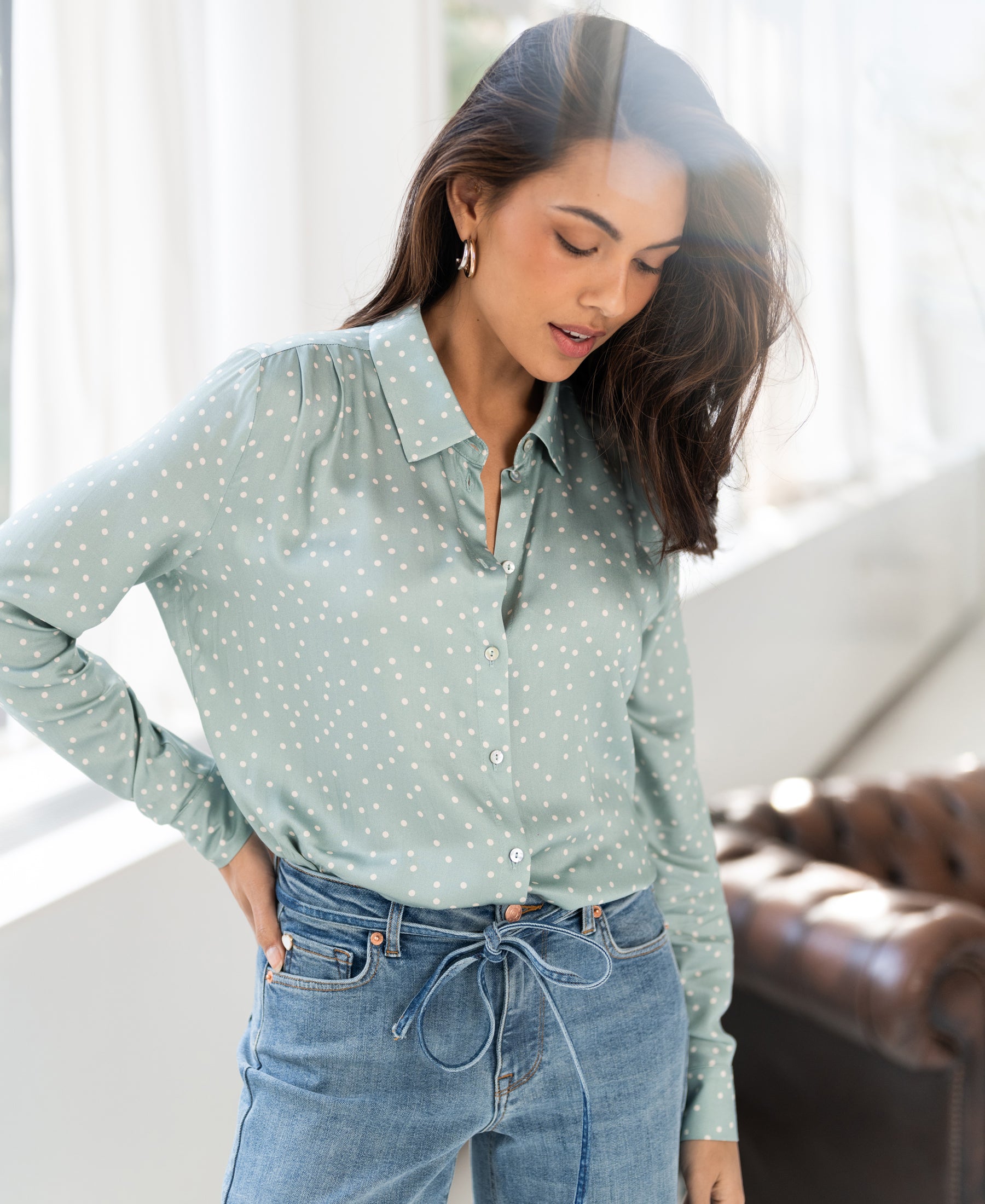 Light green and ivory polka dot blouse by PLEIN PUBLIQUE, shown worn indoors, model looking down.