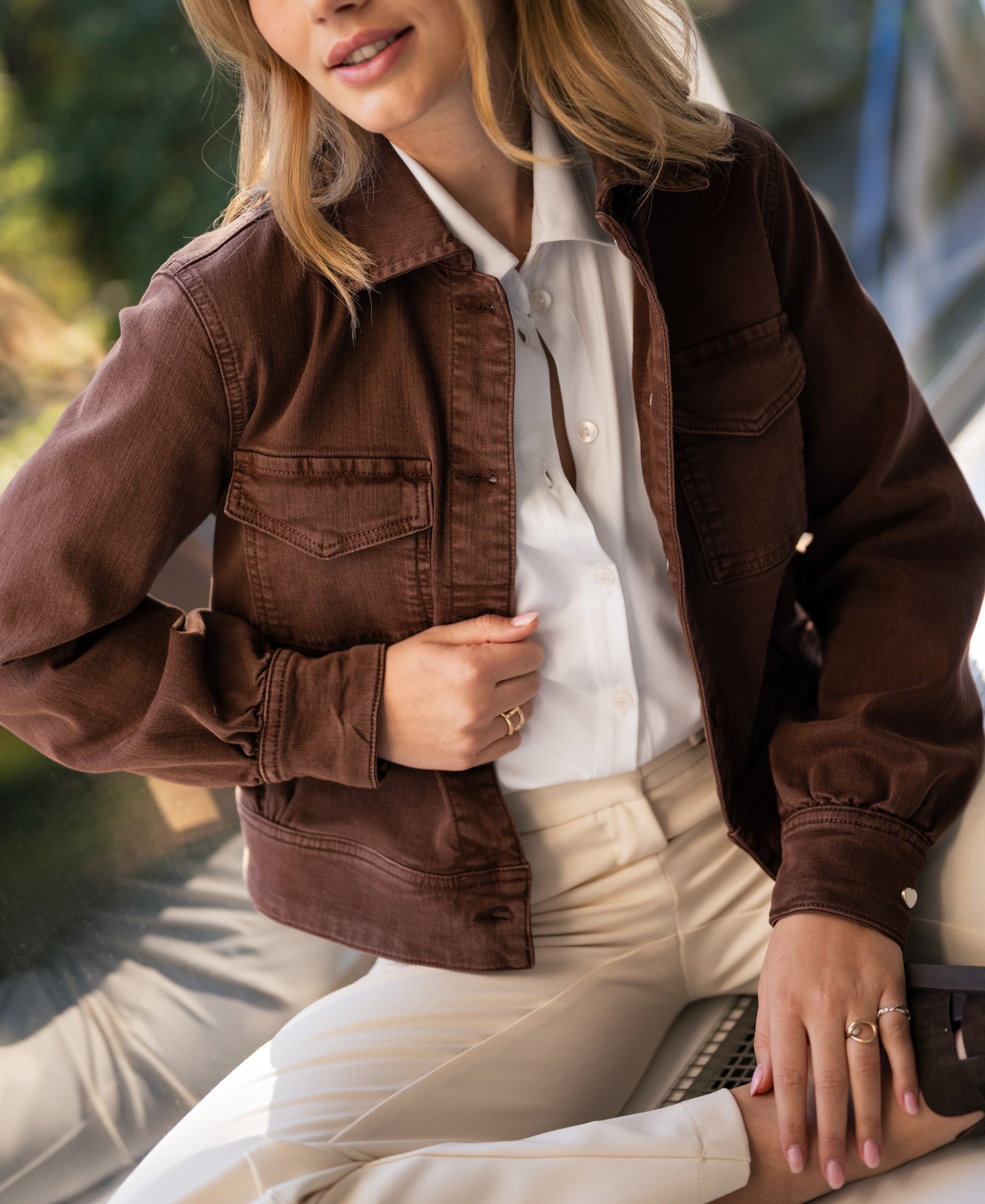 Stretch denim jacket LA CALLAS in cacao by PLEIN PUBLIQUE, shown indoors on a smiling woman.