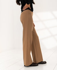 Wide-leg trousers in camel by PLEIN PUBLIQUE shown in a bright, minimal white room.