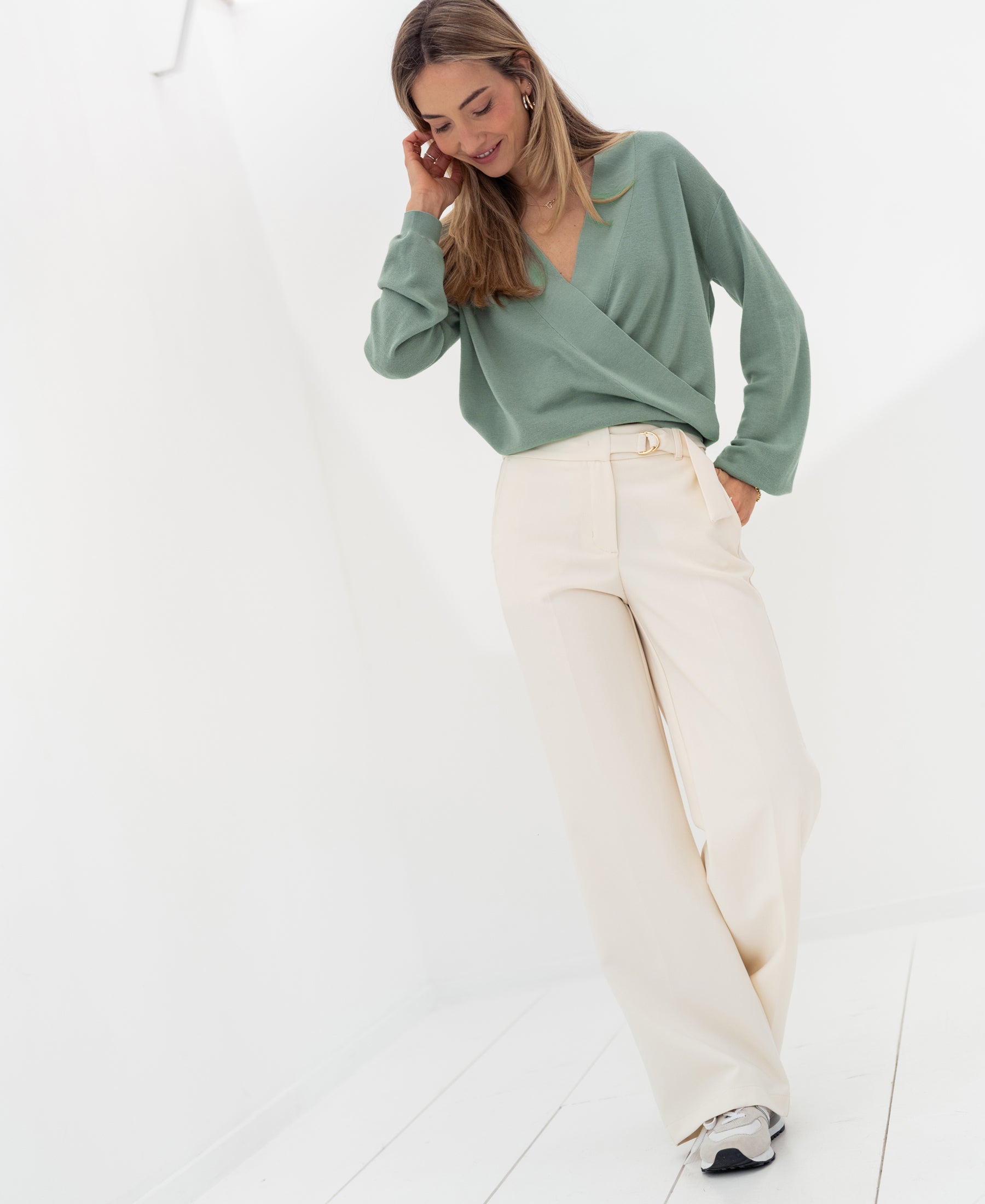 Cream-colored LA WENDE pants by PLEIN PUBLIQUE, shown worn by a woman standing in a bright room.