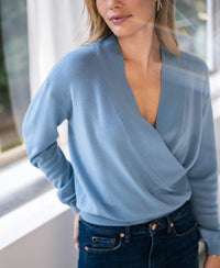 Woman wearing the LES CINQ Denim Blue Wrap Sweater from PLEIN PUBLIQUE.