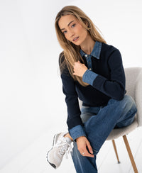 Dark blue PLEIN PUBLIQUE LA COLLEGE sweater blouse displayed on a woman in a bright room.