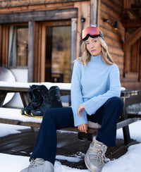 Light blue LA COZY turtleneck sweater by PLEIN PUBLIQUE displayed on a snowy bench.