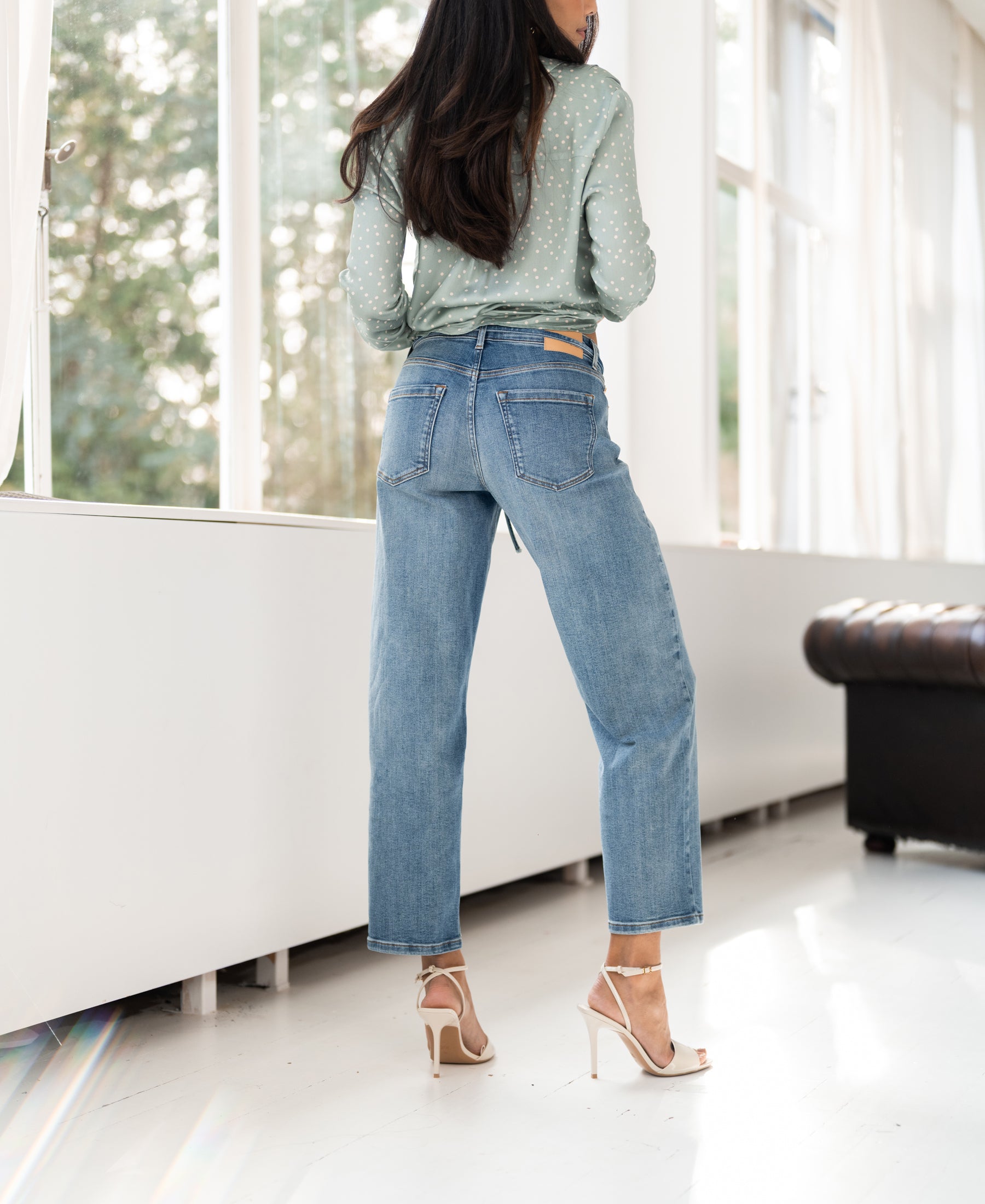 Cropped jeans in light stone wash, highlighted by natural light indoors.