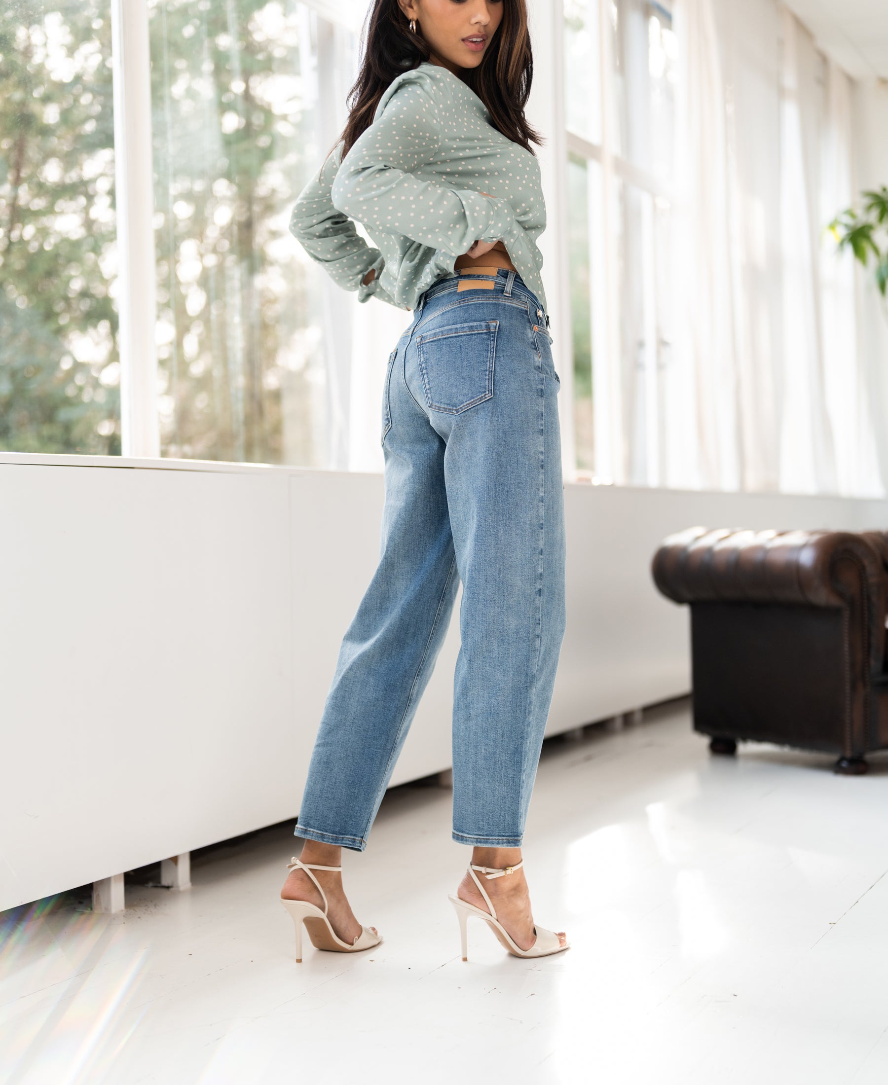 Light stone blue cropped jeans shown in a bright modern room.