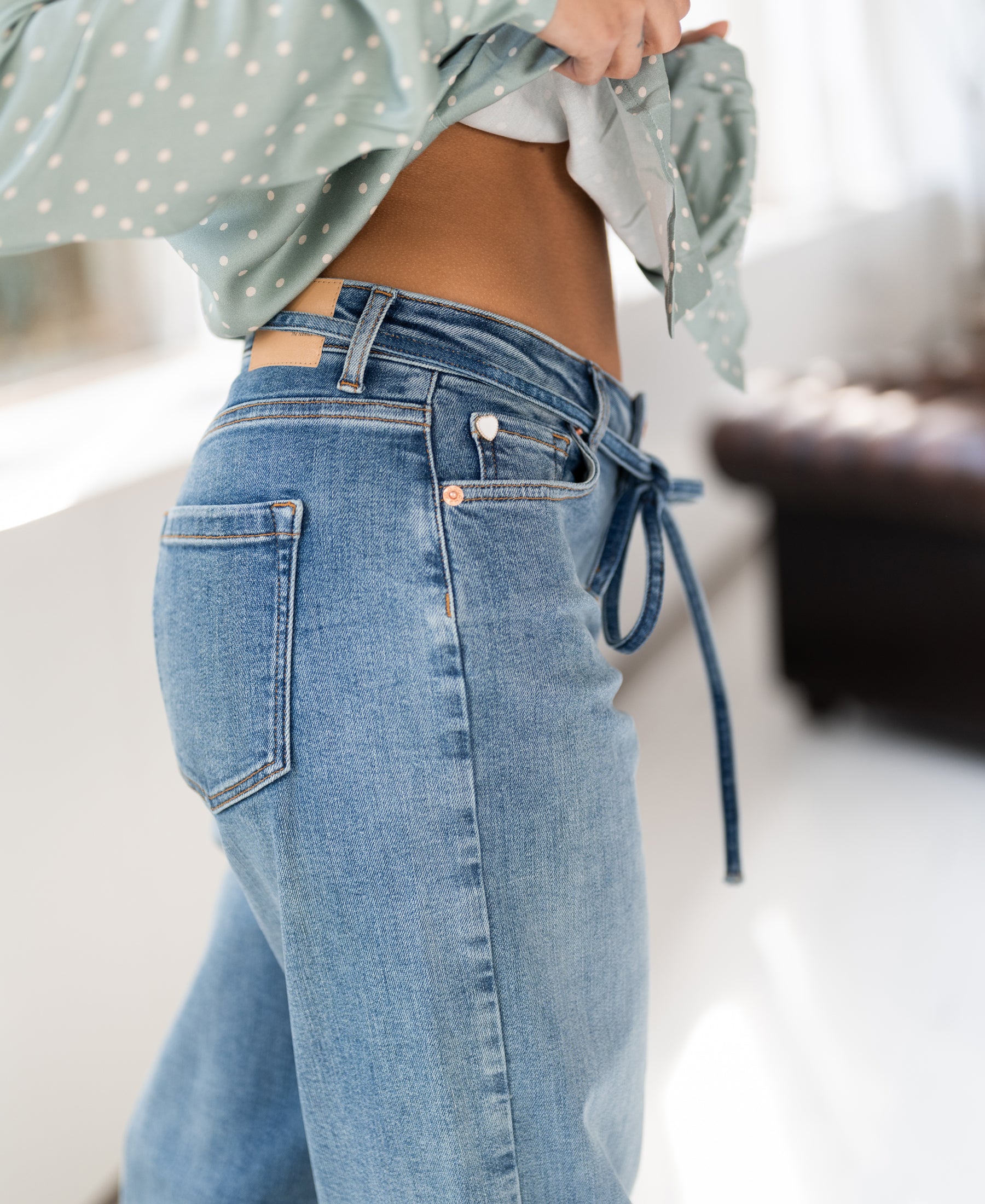 Model wears light stone wash cropped jeans, showing the waist.