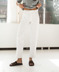 A person wears cropped white jeans indoors in bright natural light.